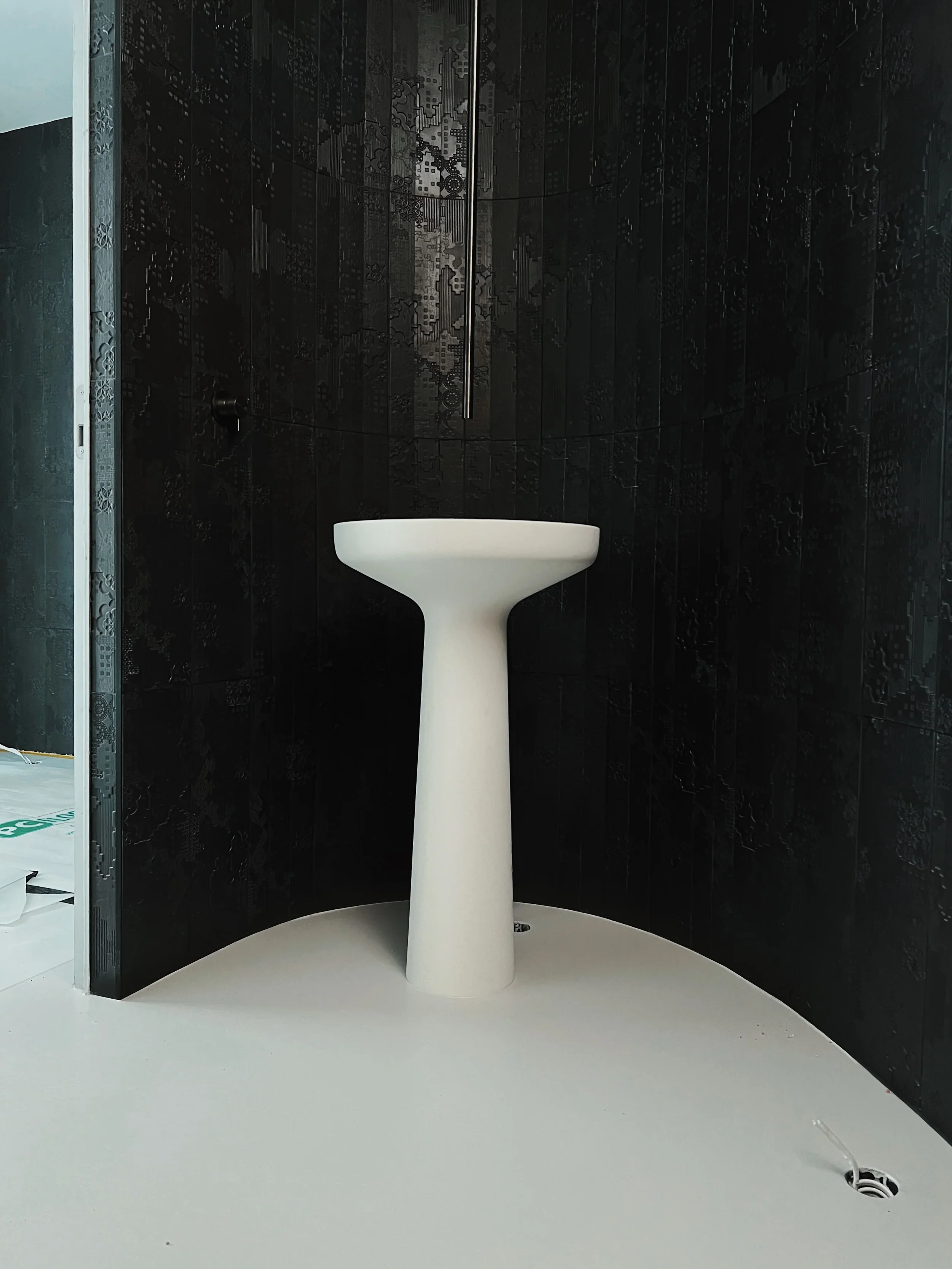 Freestanding white pedestal basin with a black Mutina textured tile feature wall.