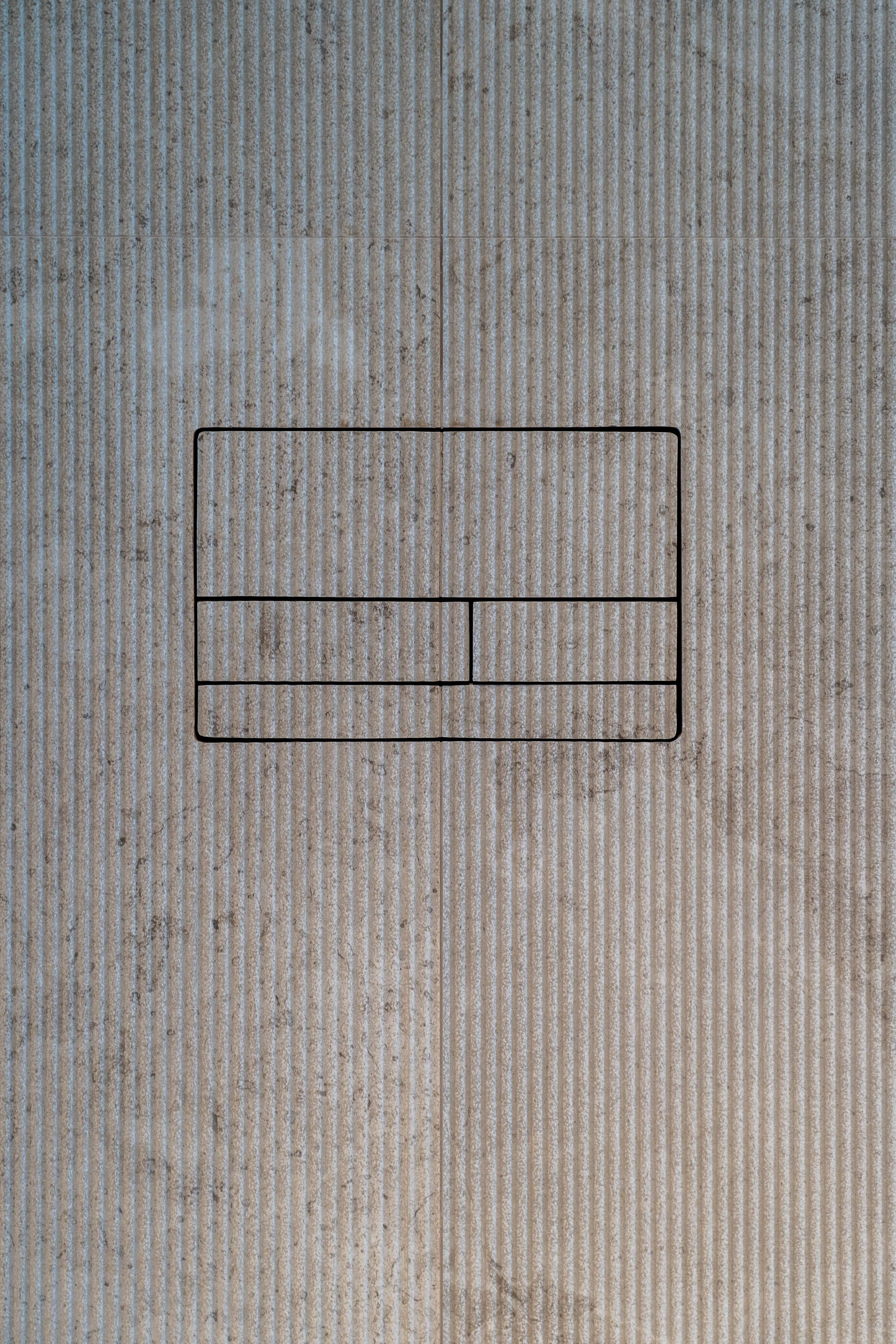 Close-up detail of a minimalist Clanea flush plate seamlessly integrated into high-end textured porcelain wall tiles, supplied and installed by PietraCasa.