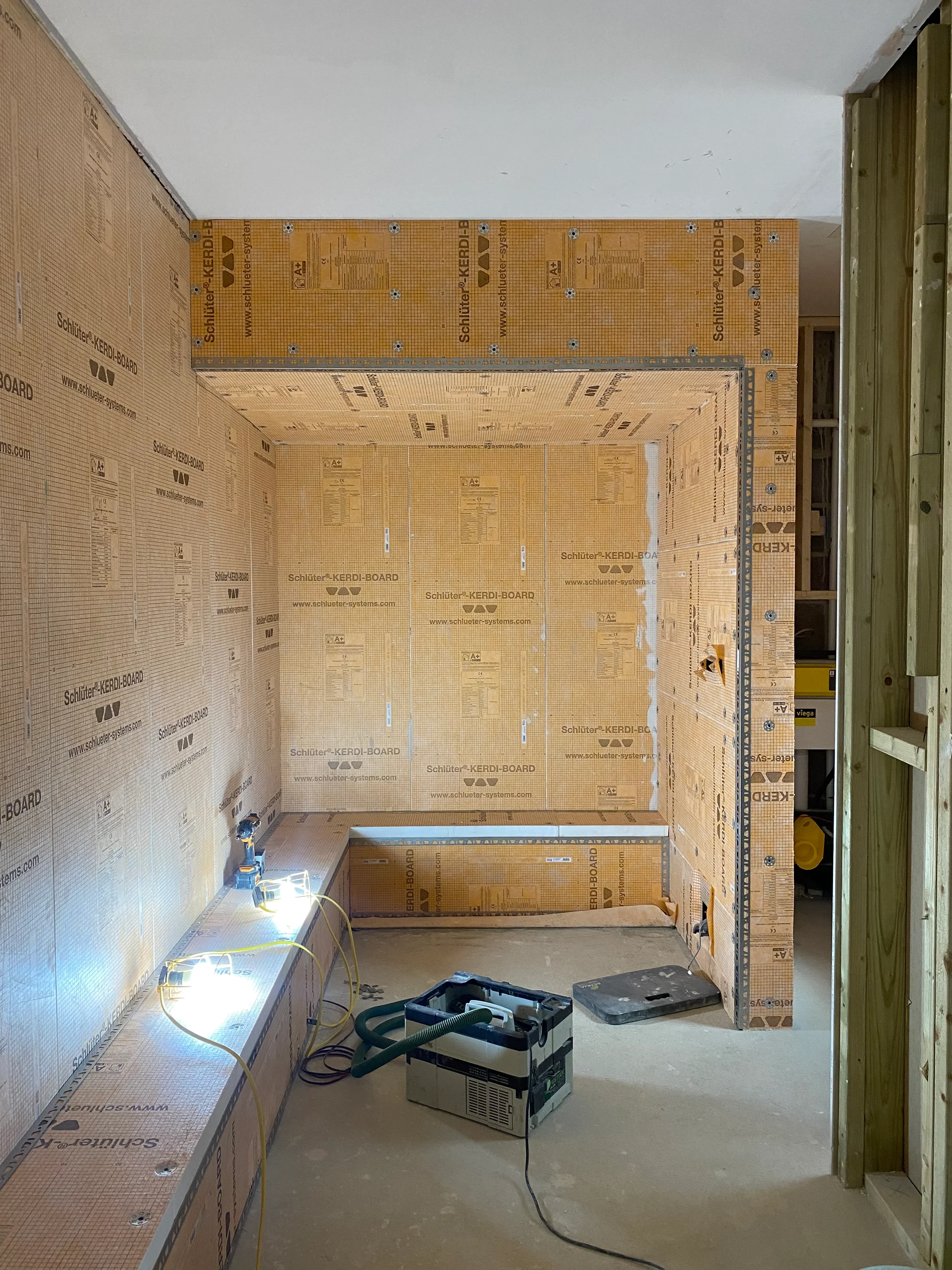 Bespoke steam room under construction featuring fully installed orange Schlüter-KERDI-BOARD waterproofing wall panels.