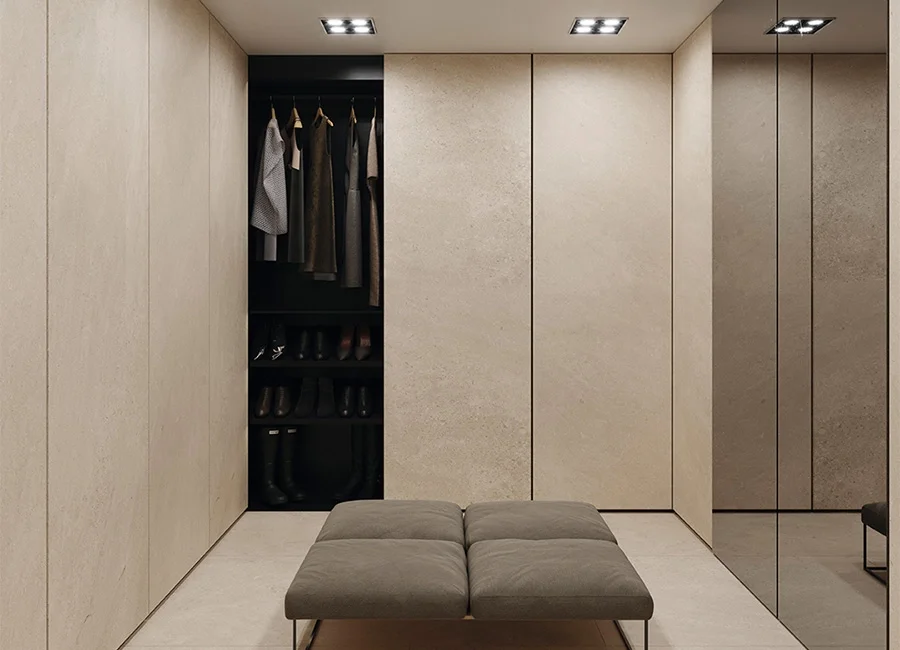 Minimalist bespoke dressing room featuring walls and seamless push-to-open wardrobe doors clad in Inalco Petra Crema, a large-format MDi porcelain surface, exclusively distributed in the UK by PietraCasa.