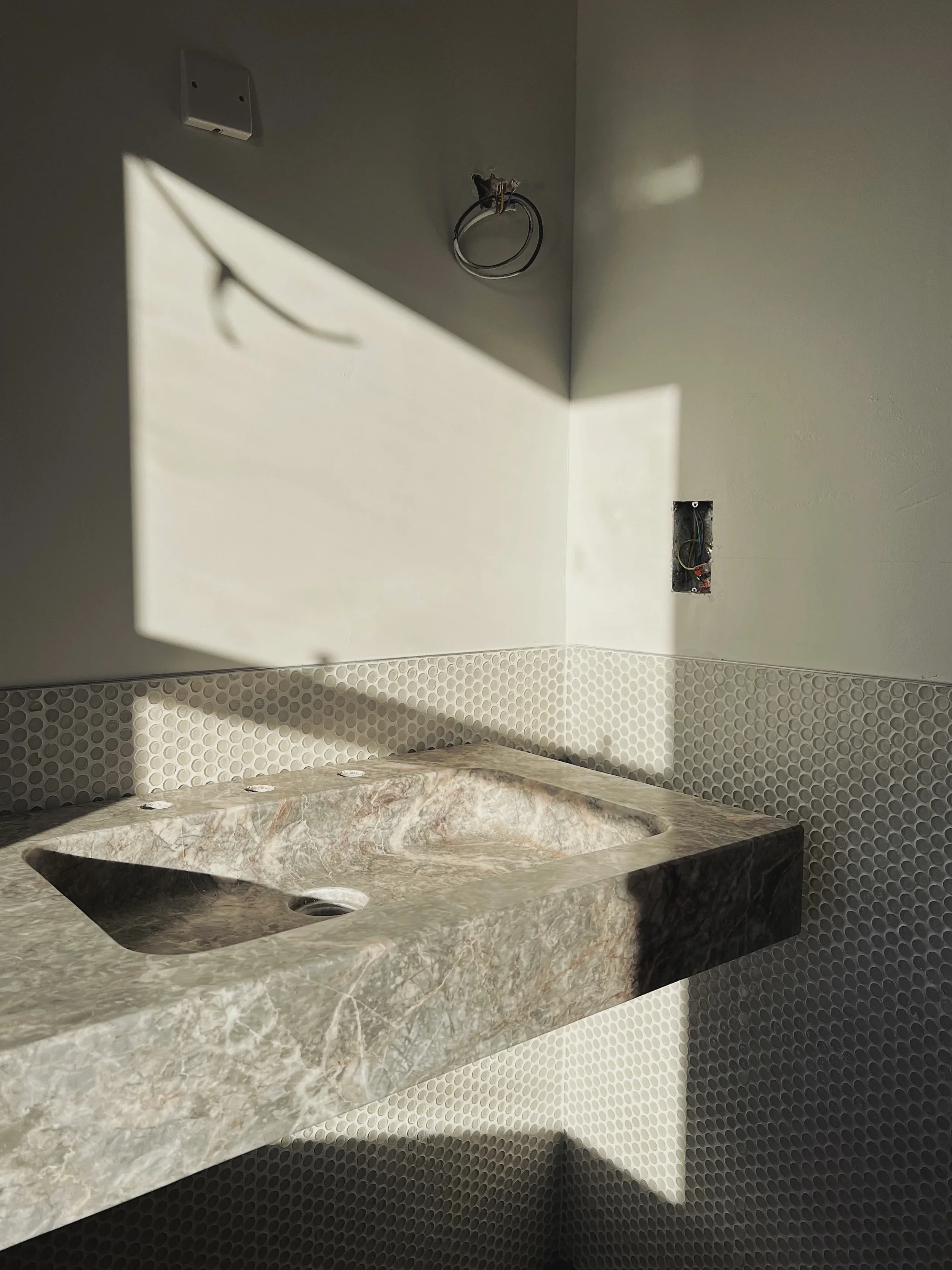 featuring a bespoke wall-mounted stone basin with a sloping integrated sink basin