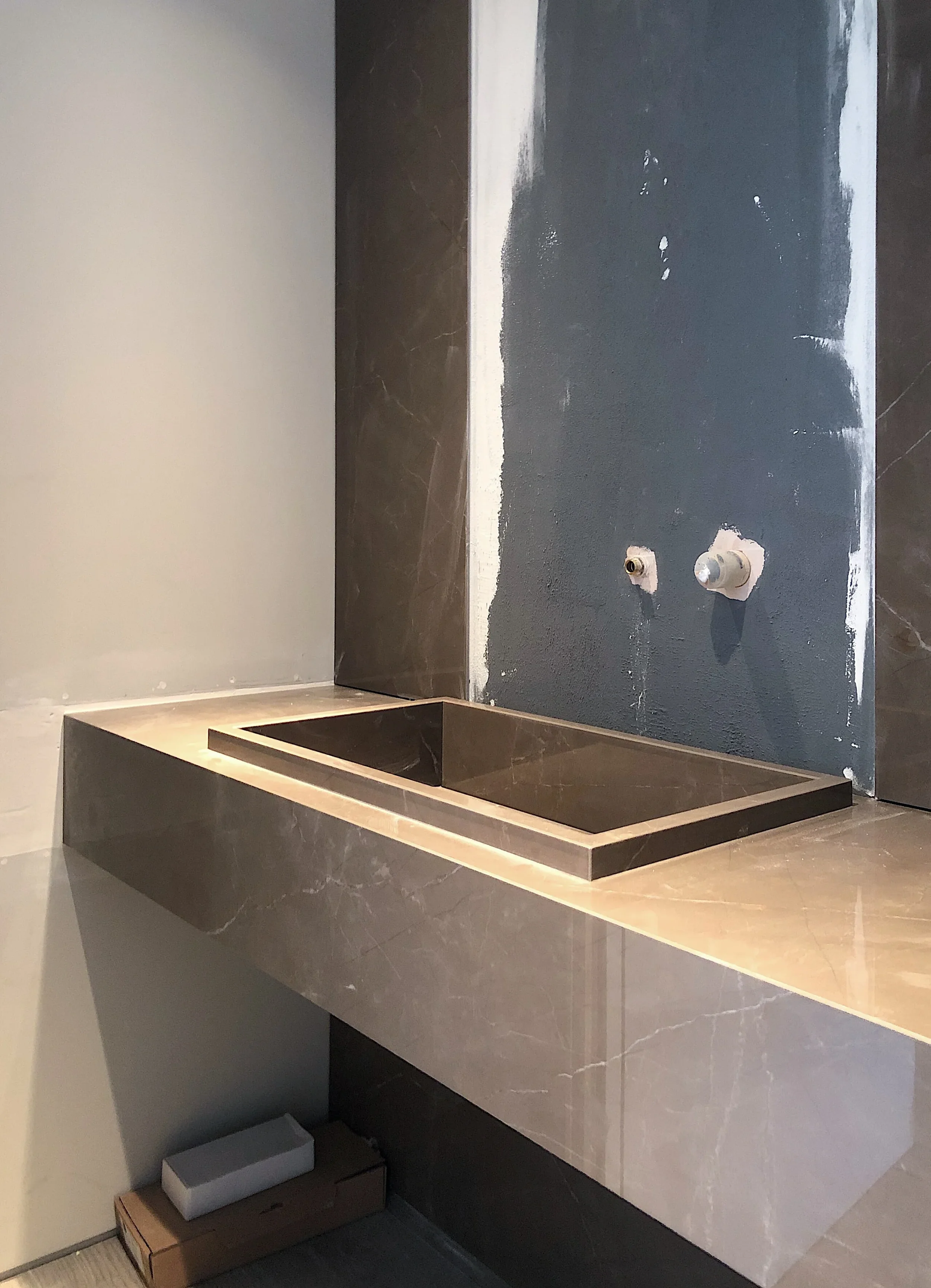 Bespoke marble-effect porcelain floating vanity and integrated sink unit under construction.
