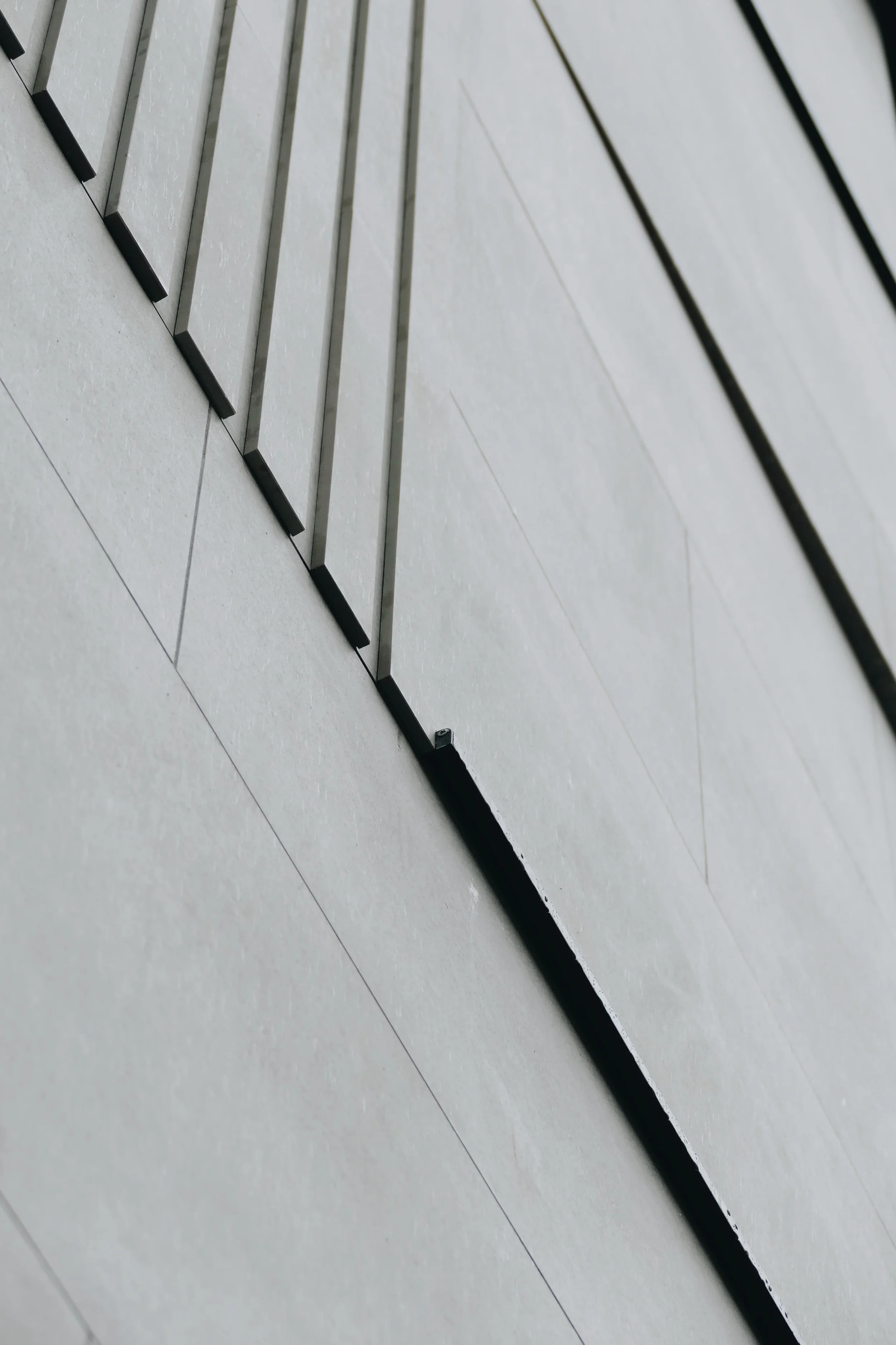 Close-up of modern architectural porcelain cladding, showcasing precise geometric lines and minimalist panel transitions.