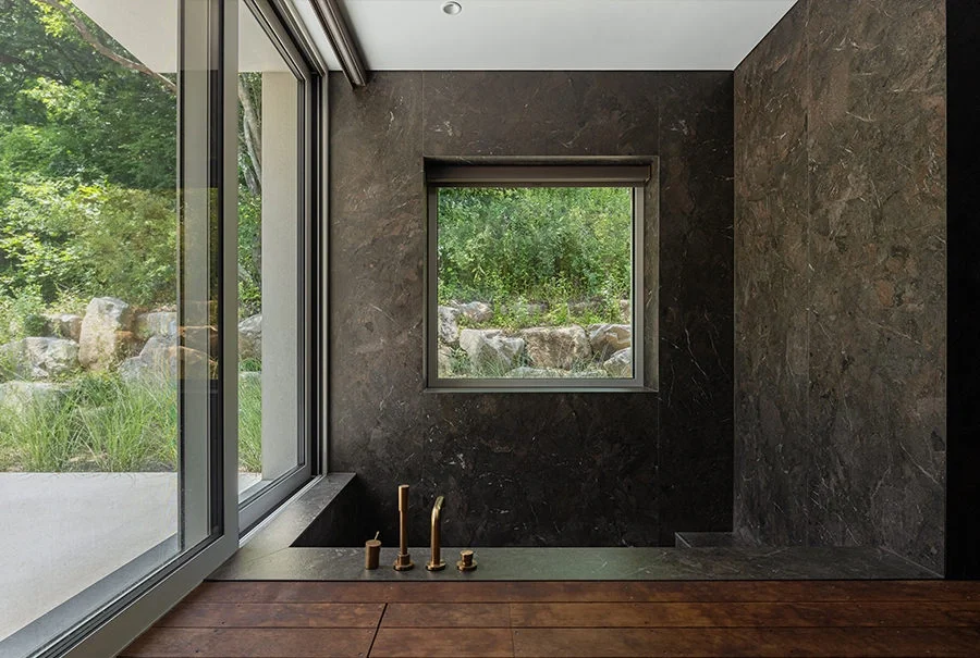 Modern bathroom featuring dark, textured wall claddings and a custom integrated bathtub made from Inalco MDi surfaces, exclusively distributed in the UK by PietraCasa.