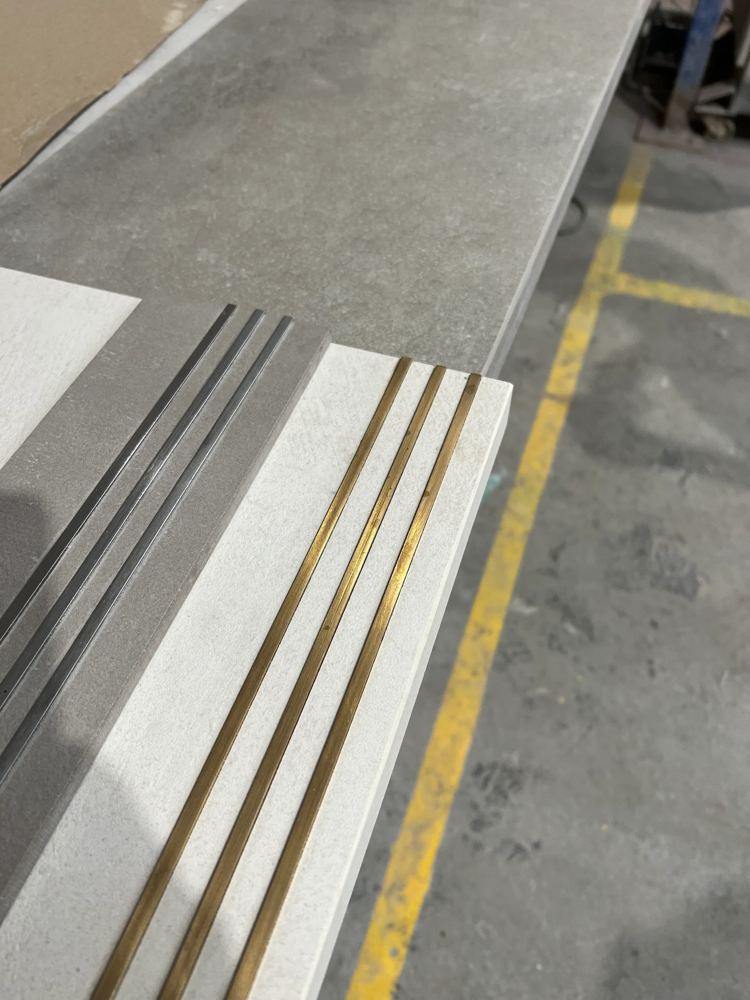 Close-up of premium brass and silver metallic non-slip strip inserts inlaid into custom porcelain step treads.