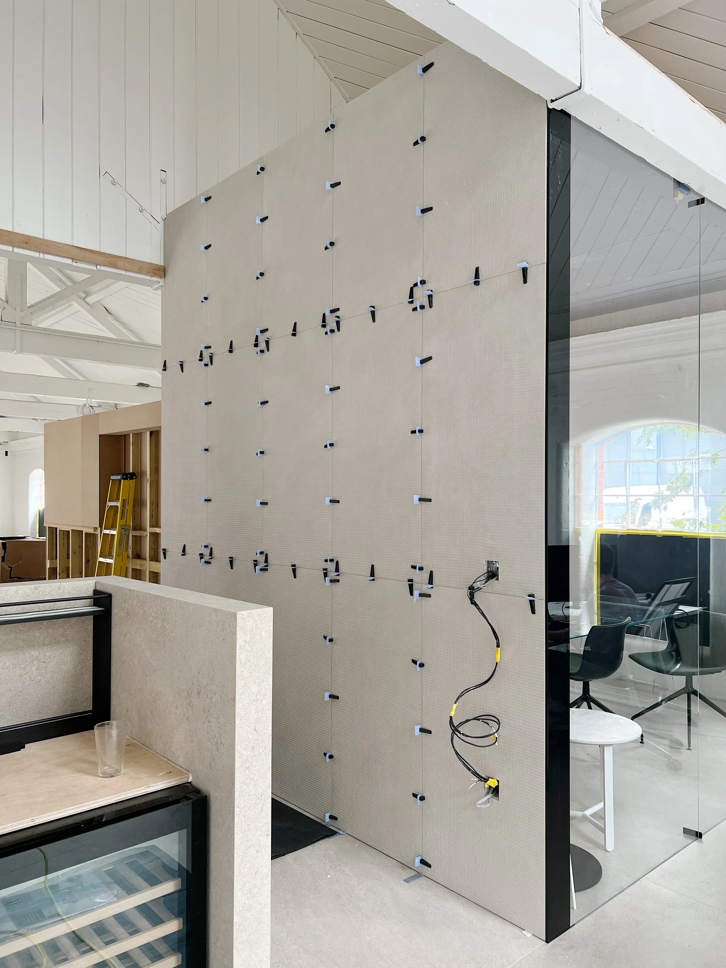 PietraCasa x abitalia showroom interior under construction, showcasing the precise installation of large-format porcelain wall cladding panels secured with tile leveling clips.