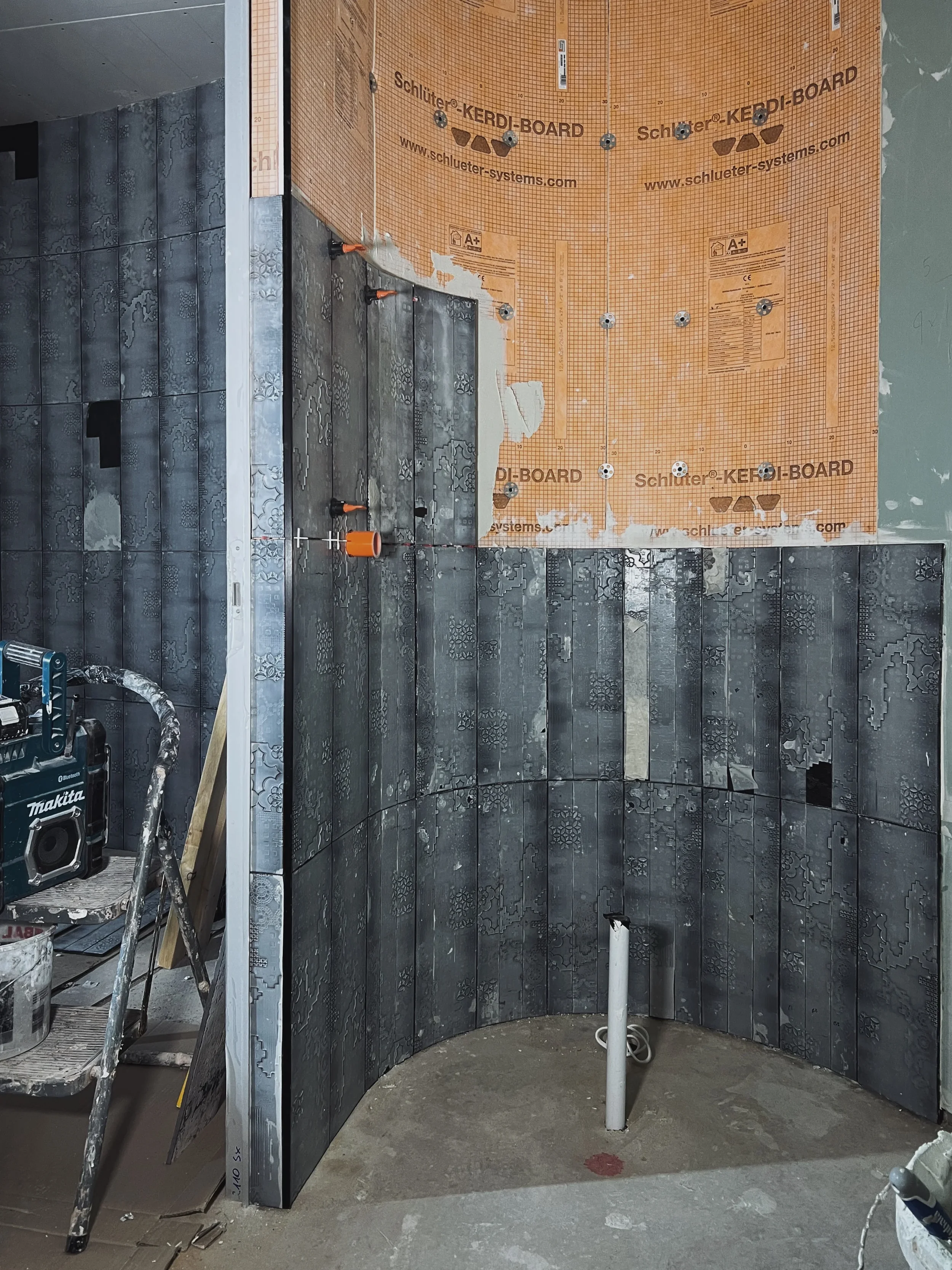 Installation of textured porcelain tiles on a curved shower wall.