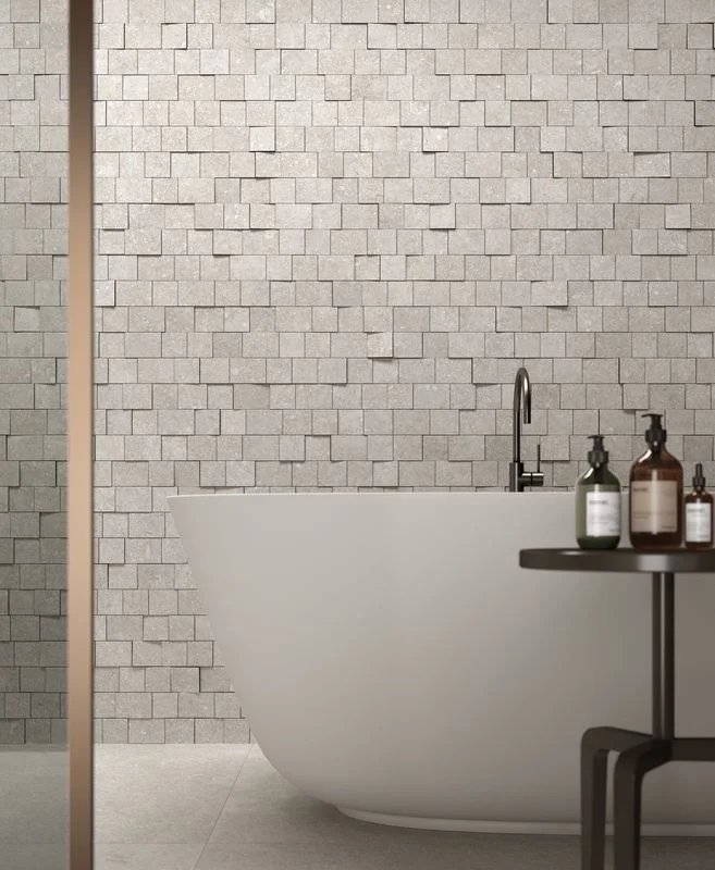 A bathroom interior featuring the Kronos Le Reverse porcelain tiles on the wall, known for their modular, multi-sized blocks that create a dynamic 3D relief effect, available through PietraCasa."  Meta Description: "Discover