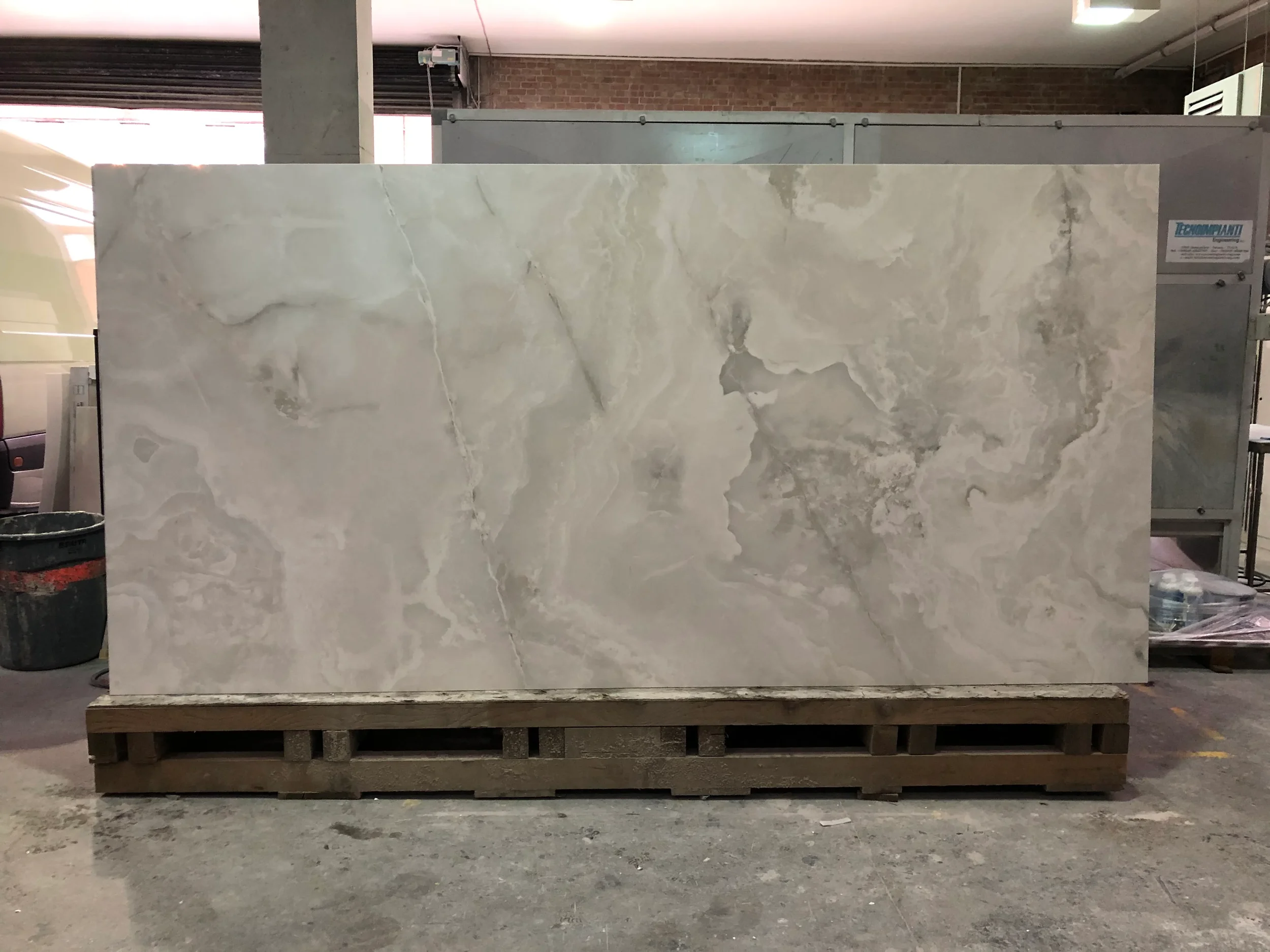 A high-quality, large-format onyx-effect porcelain slab featuring elegant, flowing neutral veining, ready for bespoke luxury architectural installation.