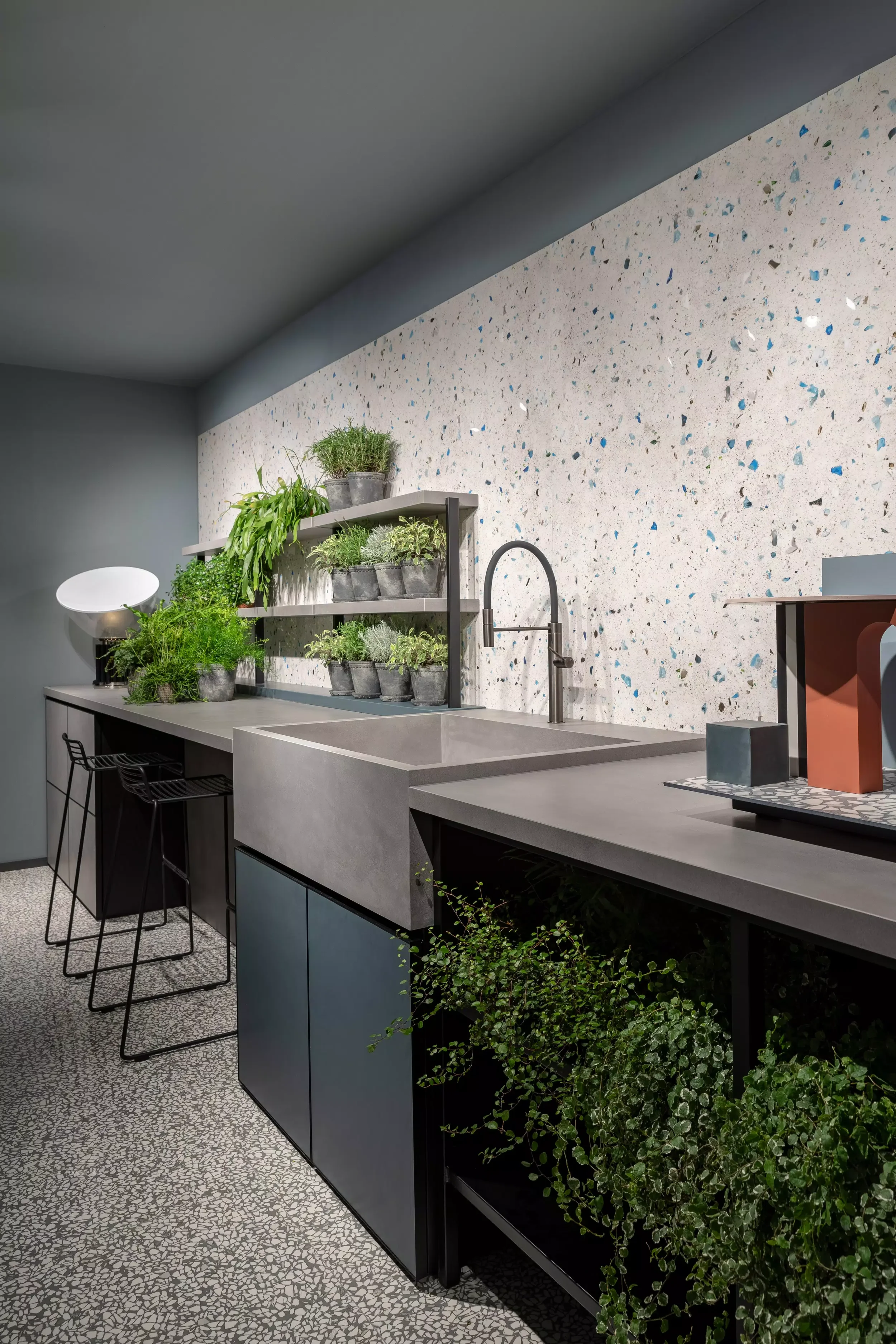 Modern concrete and terrazzo kitchen display featuring a monolithic concrete-style sink and worktops crafted from Florim stone, paired with striking blue-flecked terrazzo wall cladding and flooring, supplied and installed by PietraCasa.