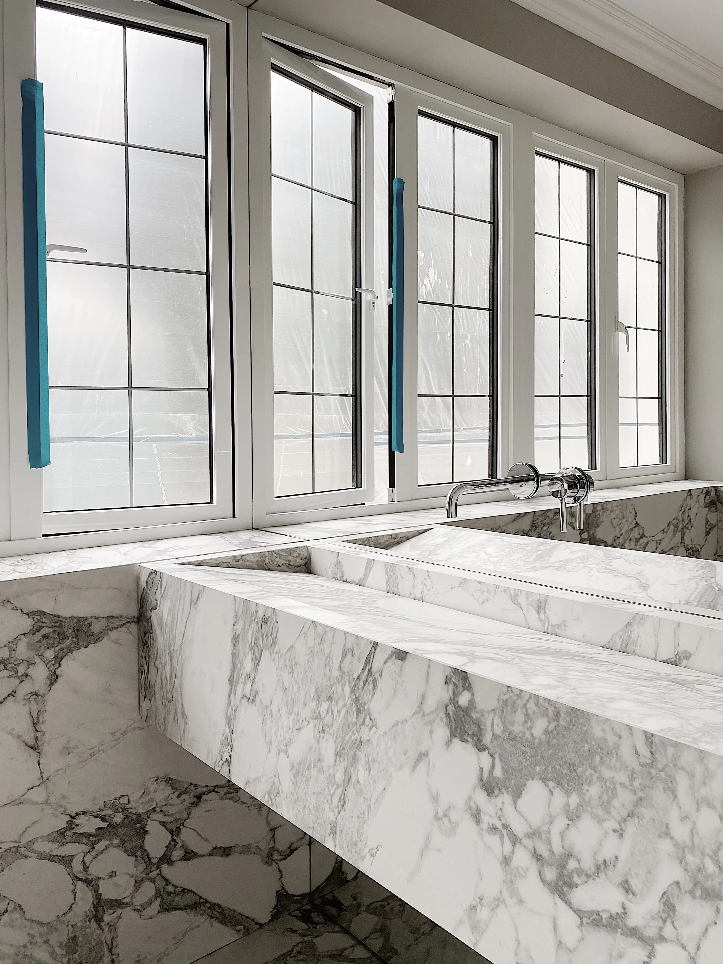 A luxury bespoke double vanity unit with fully integrated slot sinks, crafted from Arabescato marble-effect porcelain by PietraCasa during the final installation phase.