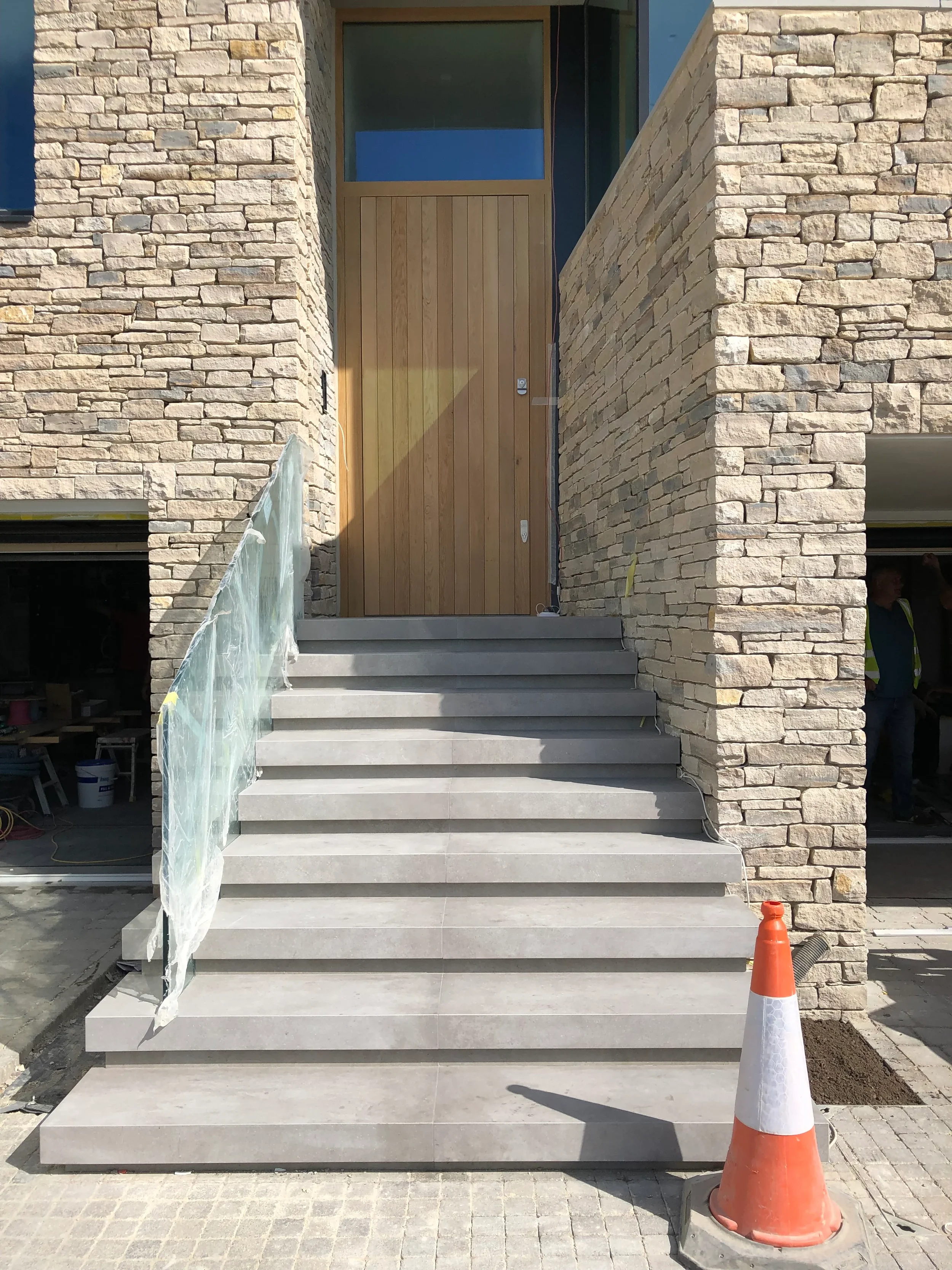 Straight-on view of contemporary external entrance stairs clad in large-format matte grey porcelain tiles.