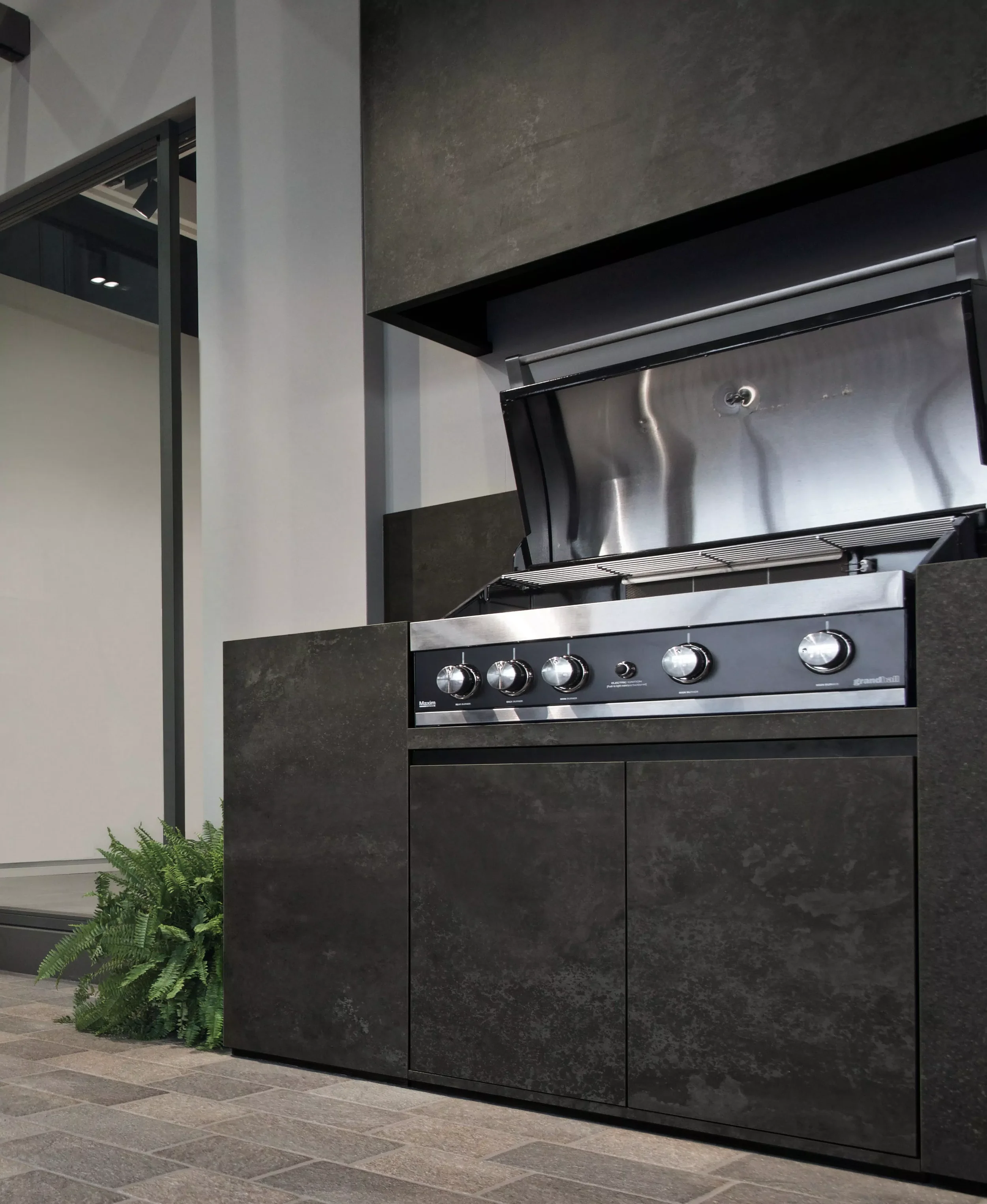 Modern outdoor kitchen island clad in durable FLORIM stone porcelain slabs, featuring a sleek, integrated built-in gas barbecue grill, expertly supplied and installed by PietraCasa.
