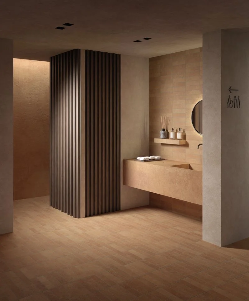 A luxurious modern bathroom featuring Kronos Ceramiche's Terra Crea collection in 'Mattone,' with clay-textured porcelain stoneware on walls and floors for a warm, enveloping look, available through PietraCasa.