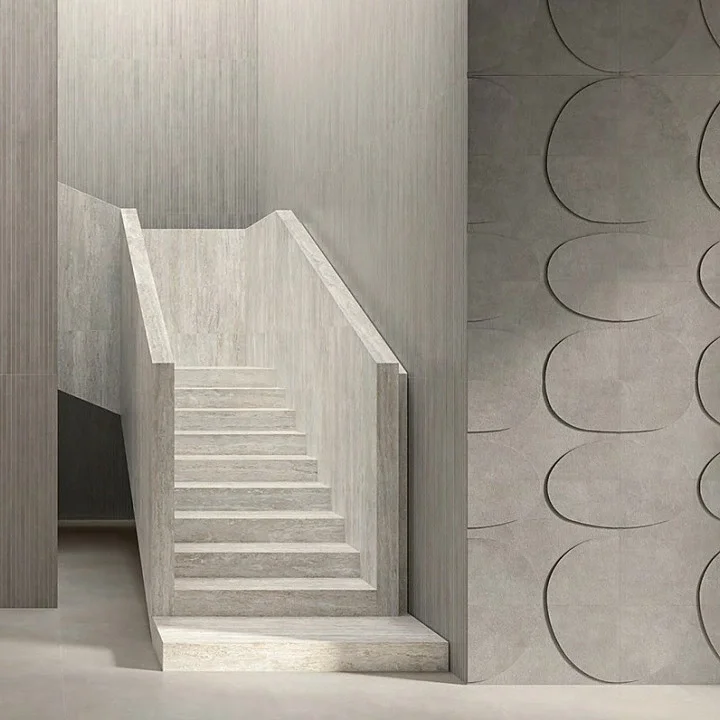 Modern minimalist interior clad in large-format porcelain stoneware from the Italgraniti I Travertini and I Cementi collections, featuring matte finishes and geometric textures, available through PietraCasa.