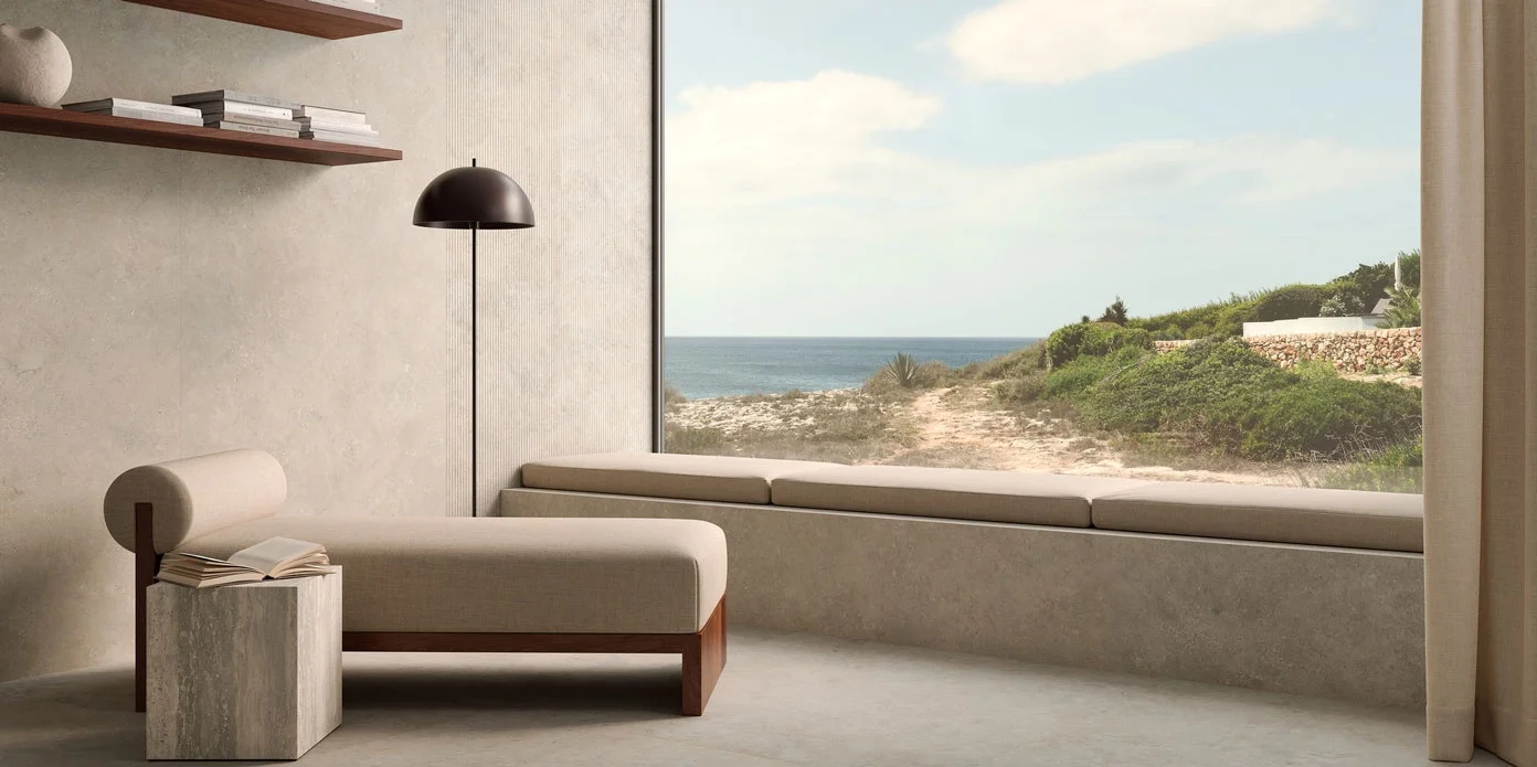 Elegant coastal lounge showcasing Marazzi Mystone Tivoli stone-effect porcelain tiles, creating a seamless, earthy transition from the indoor floors to the window seat base, available through PietraCasa.