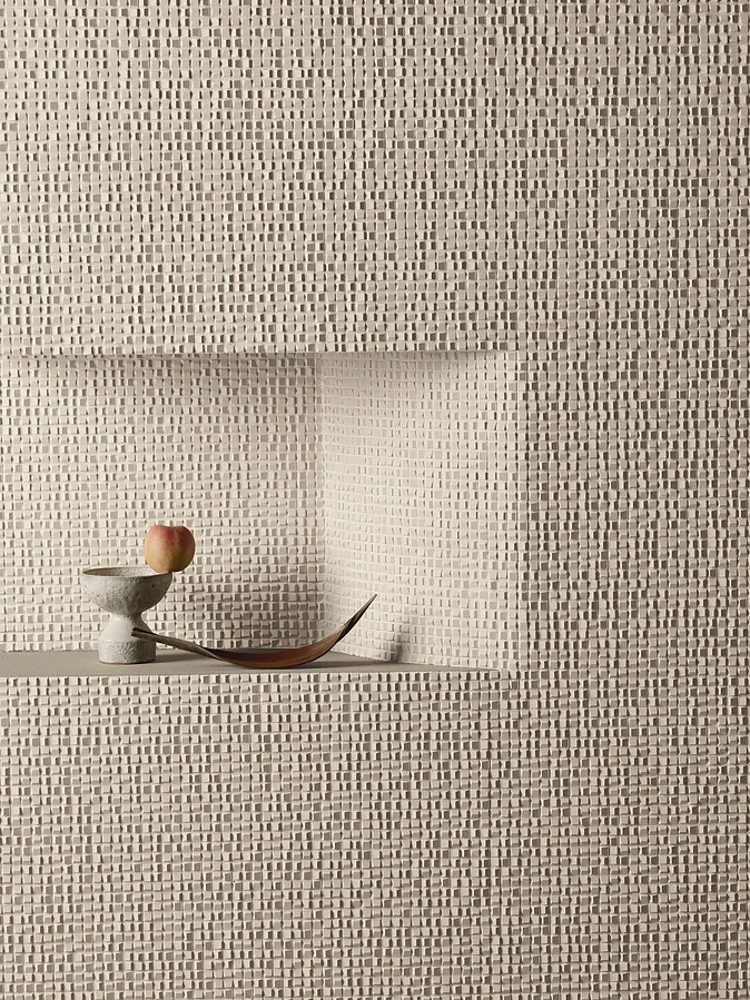 The textured wall surface features Mutina Phenomenon Air Grigio, a 3-dimensional porcelain tile designed by Tokujin Yoshioka, showcasing refined geometric texture, available through PietraCasa.