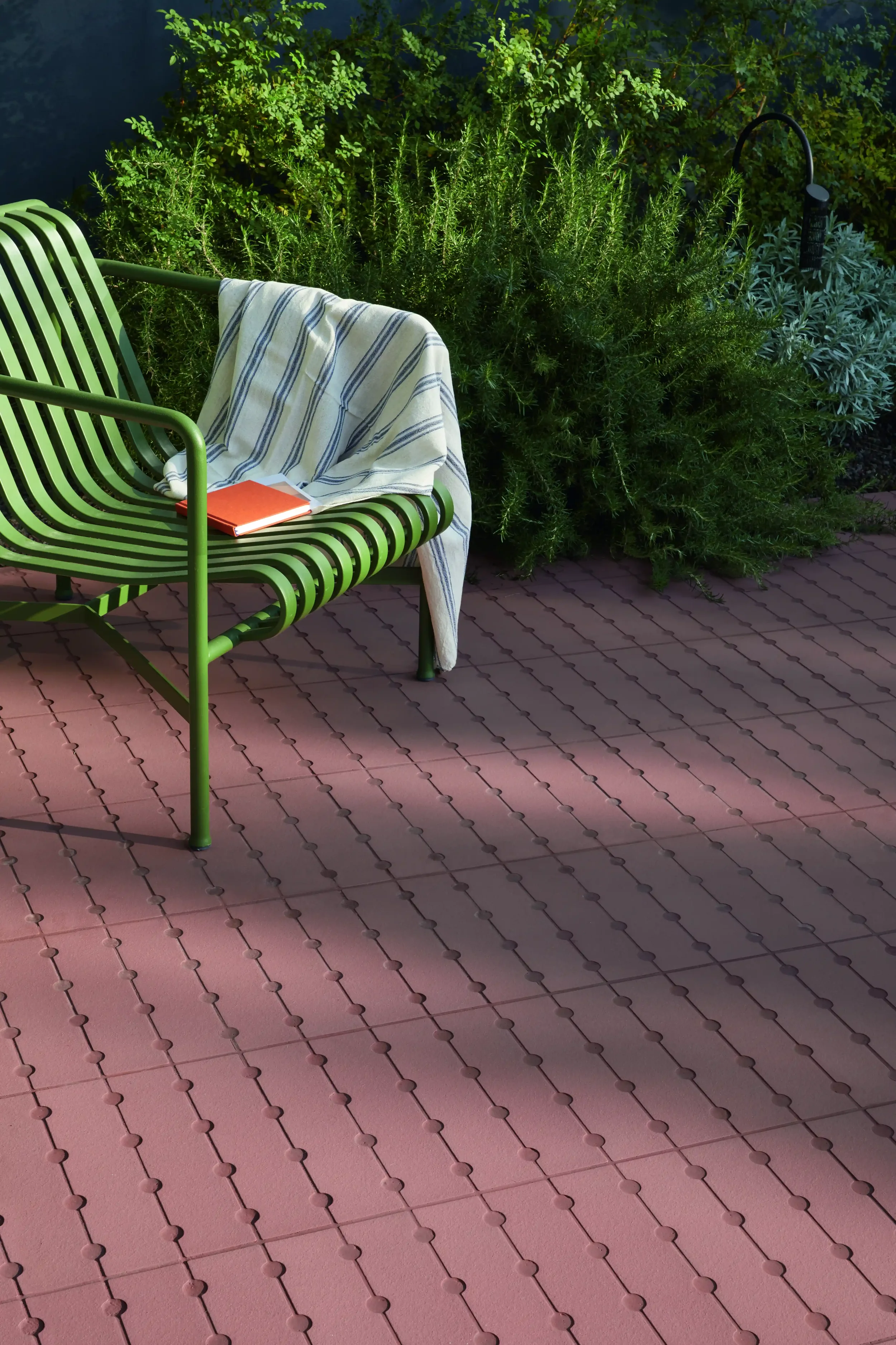 Outdoor patio setting featuring the Osso & Bottone paver collection by Mutina, showcasing intricately shaped terracotta-toned ceramic tiles, available through PietraCasa