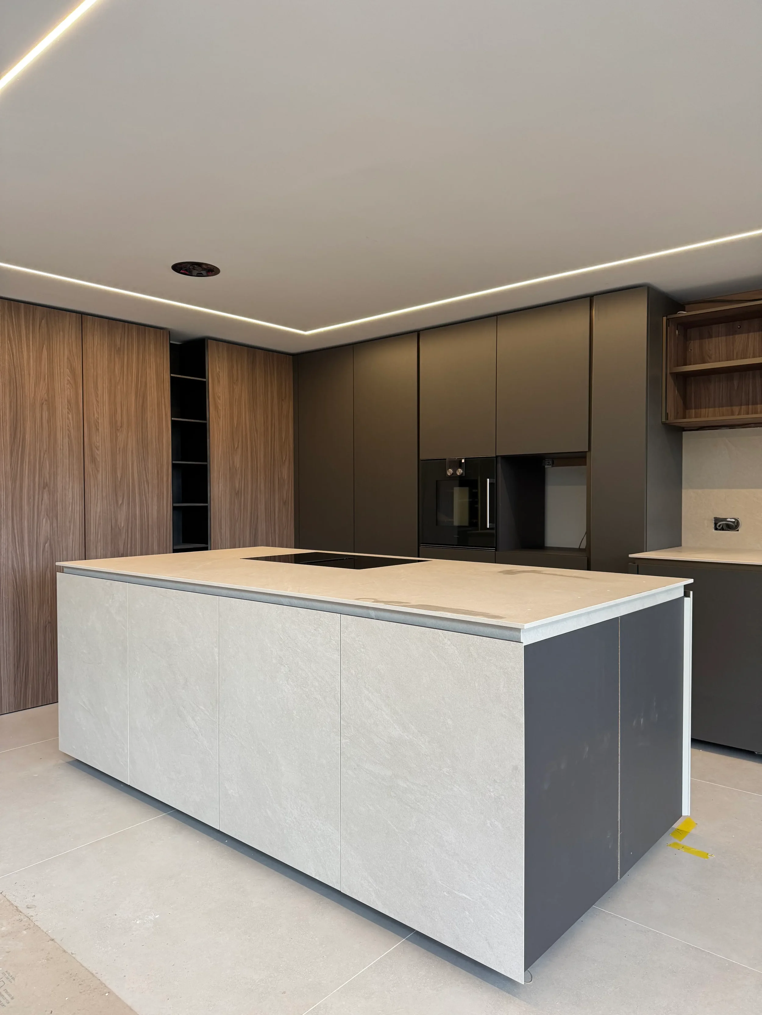 Minimalist kitchen island with light stone-effect porcelain worktops and cladding.