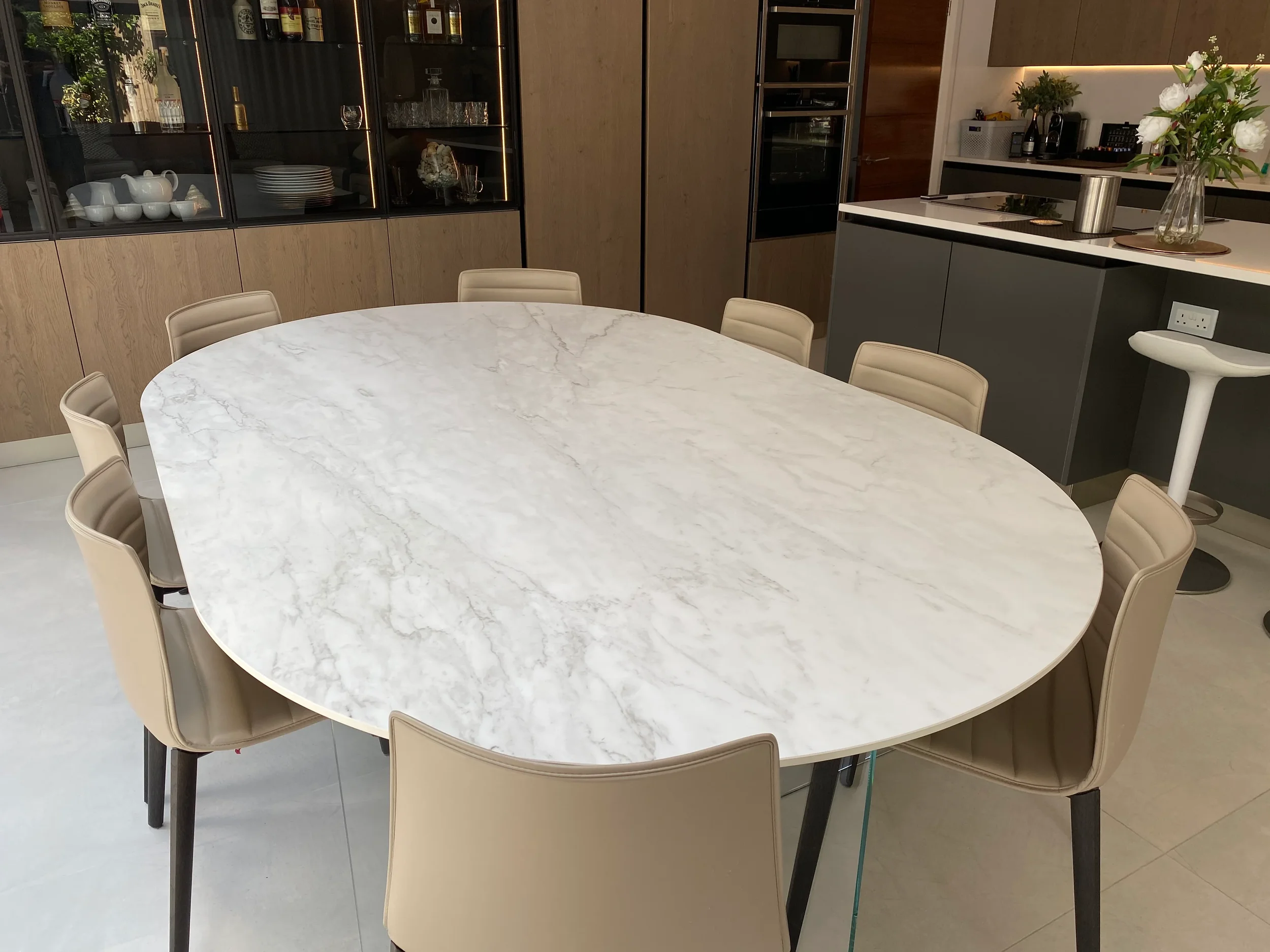 A sophisticated, modern dining area showcasing a stunning oval marble-effect porcelain table, creating a refined and cohesive focal point in the home.