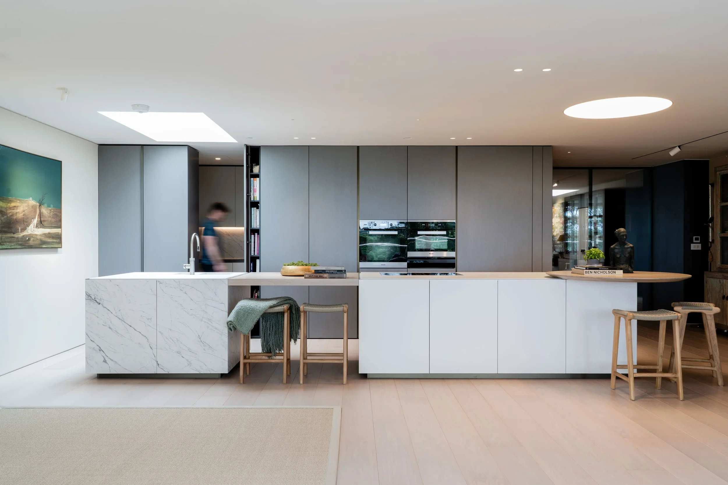 Contemporary Zampieri kitchen designed and supplied by Pietracasa and Abitalia, featuring integrated Gaggenau ovens set into sleek grey handleless floor-to-ceiling cabinets, paired with a multi-level central island featuring a white marble-effect por