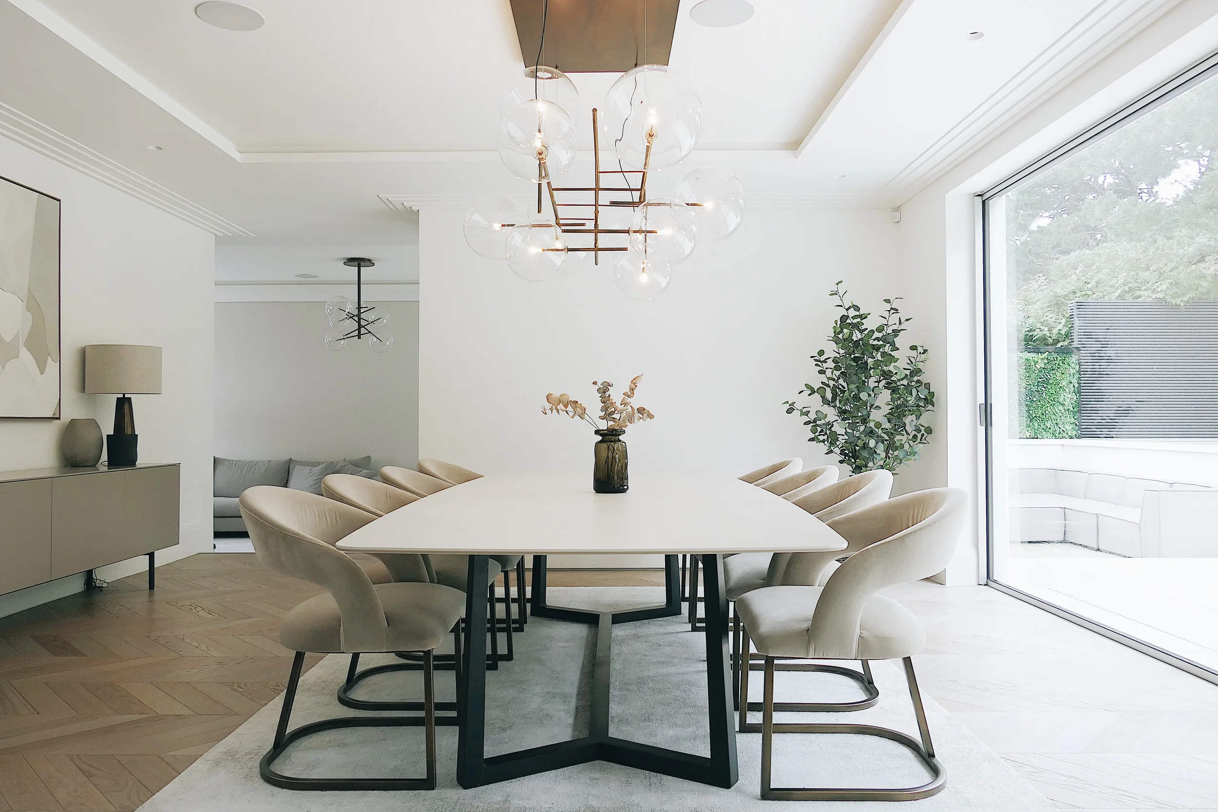 Luxury dining room featuring a bespoke dining table custom fabricated from two 6mm Inalco Pacific large-format porcelain slabs, featuring a honed top surface, hammered underside, and custom Flexform-inspired metal legs.