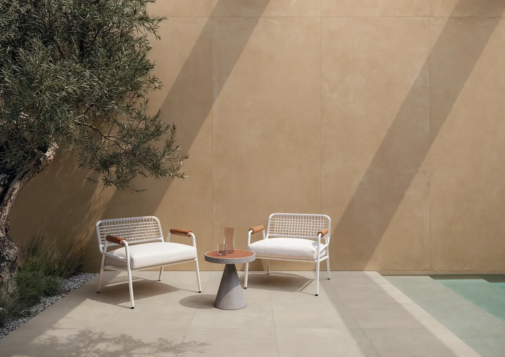 Large-format Impronta concrete-effect porcelain stoneware used in an outdoor terrace and pool-side application, supplied by PietraCasa.