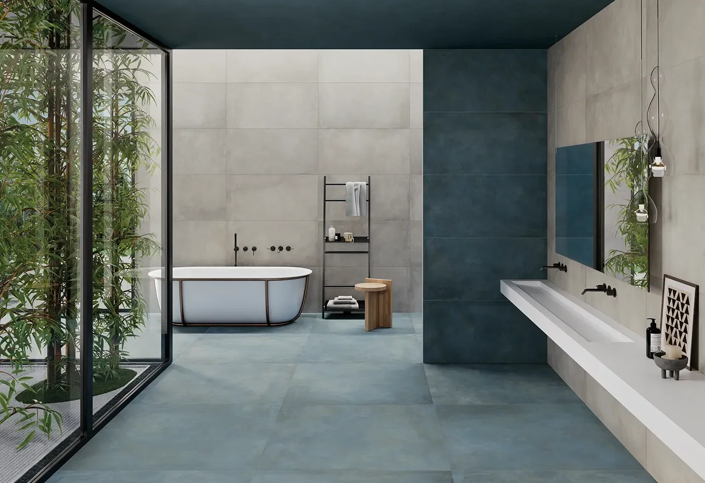 Modern bathroom interior featuring Ceramiche Keope Plate Titanium tiles, an industrial-style porcelain that mimics oxidized metal, combining cool grey walls with deep, oceanic blue floors, available through PietraCasa.