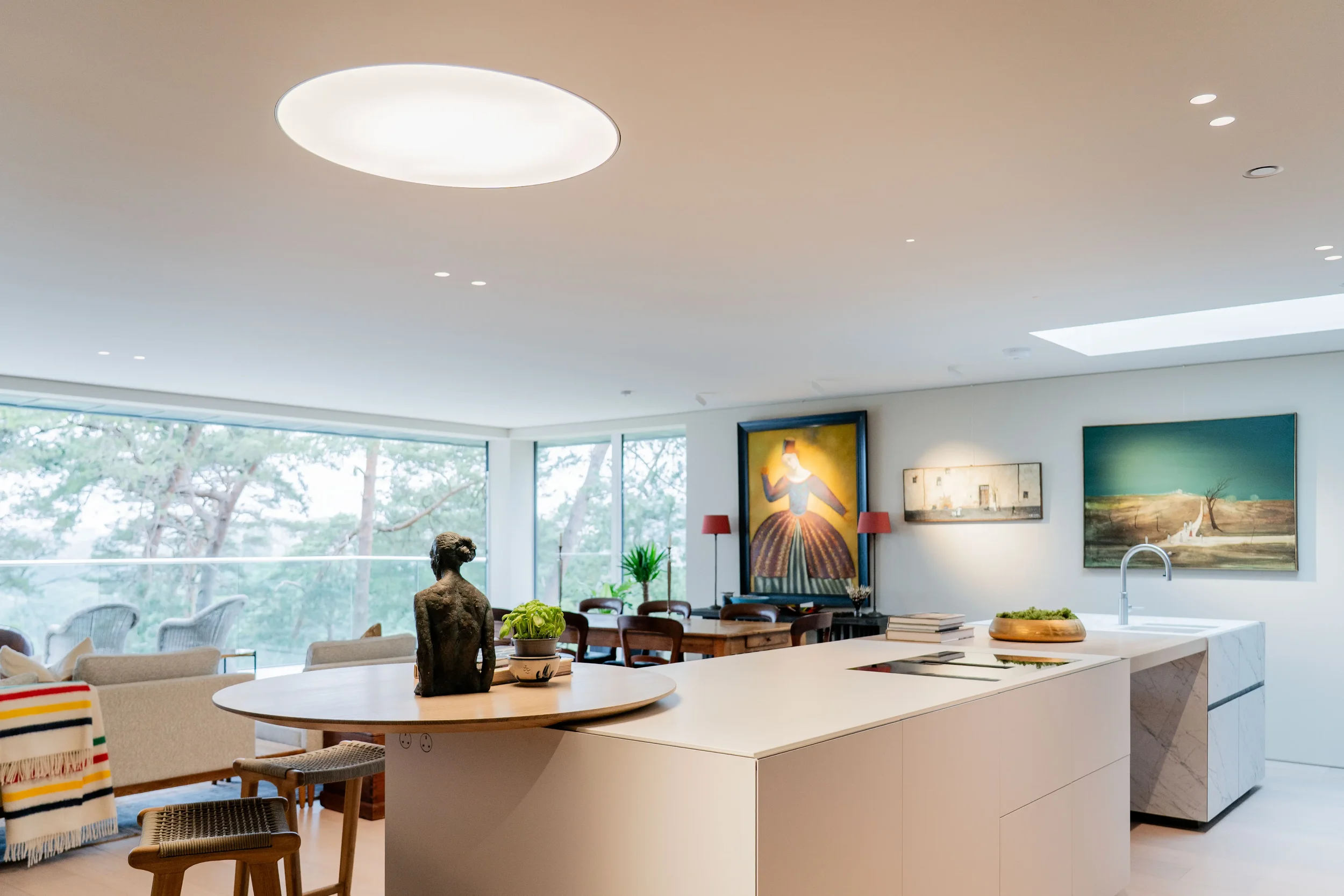 Bespoke open-plan kitchen island featuring a seamless porcelain countertop with an integrated circular wooden breakfast bar, installed by PietraCasa and Abitalia.