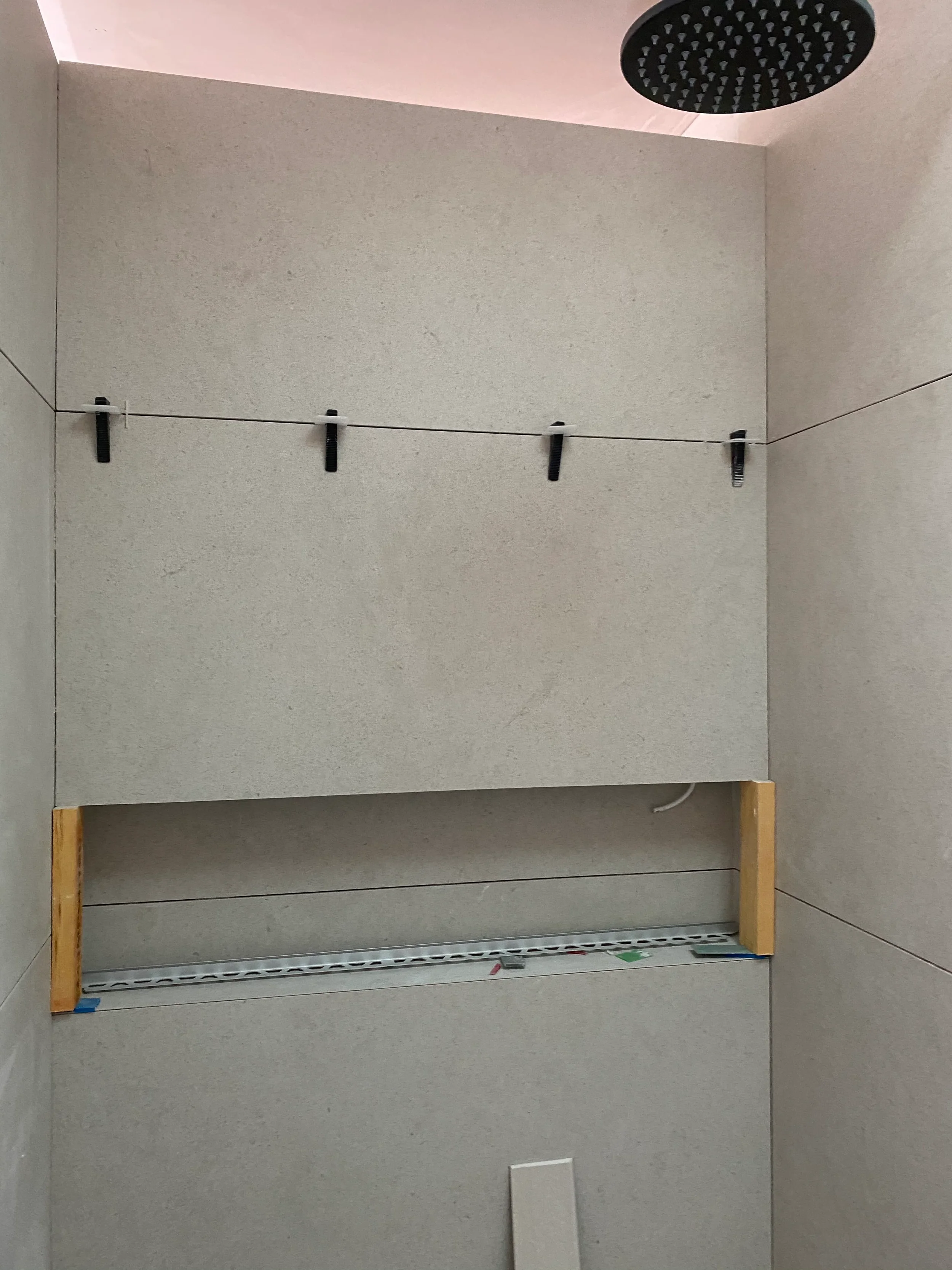 Precision installation of stone-look porcelain tiles around a built-in shower niche.