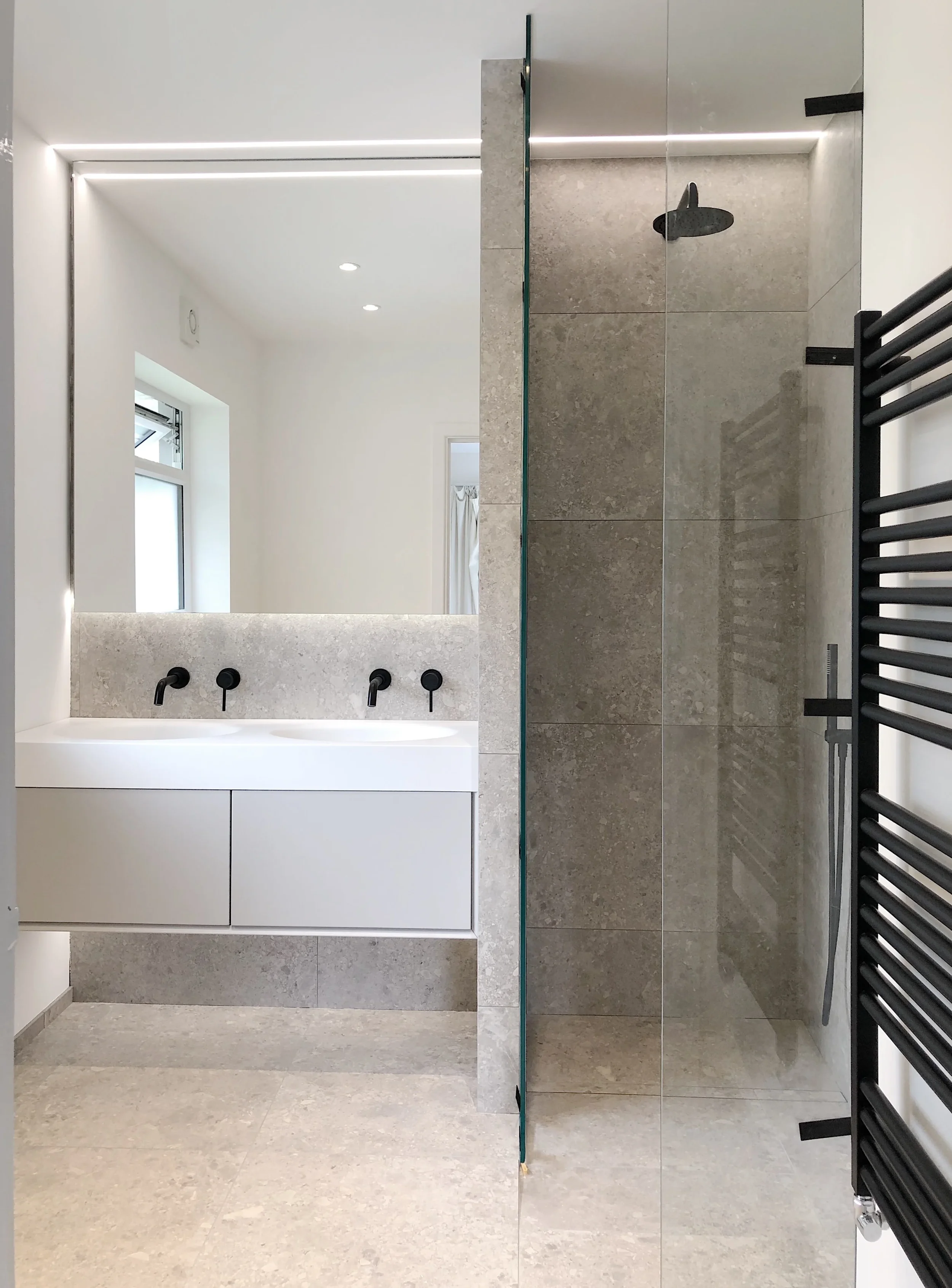 Modern floating double vanity and walk-in glass shower with grey stone-look porcelain tiling.