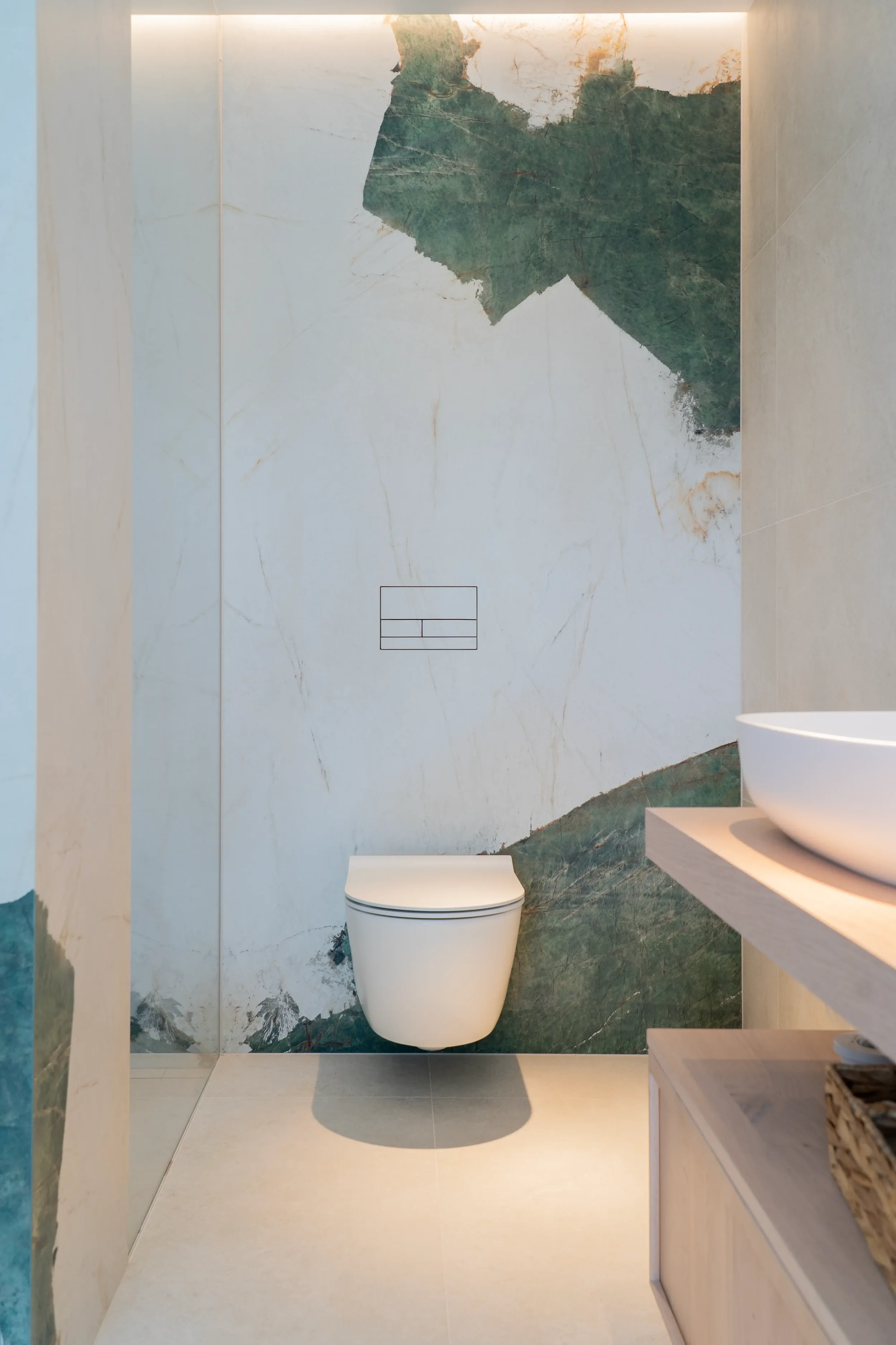 Contemporary luxury bathroom designed and supplied by Pietracasa and Abitalia, featuring a white wall-hung toilet set against a striking feature wall of Florim Heritage Luxe porcelain slabs with bold green marble-look veining, paired with a minimali