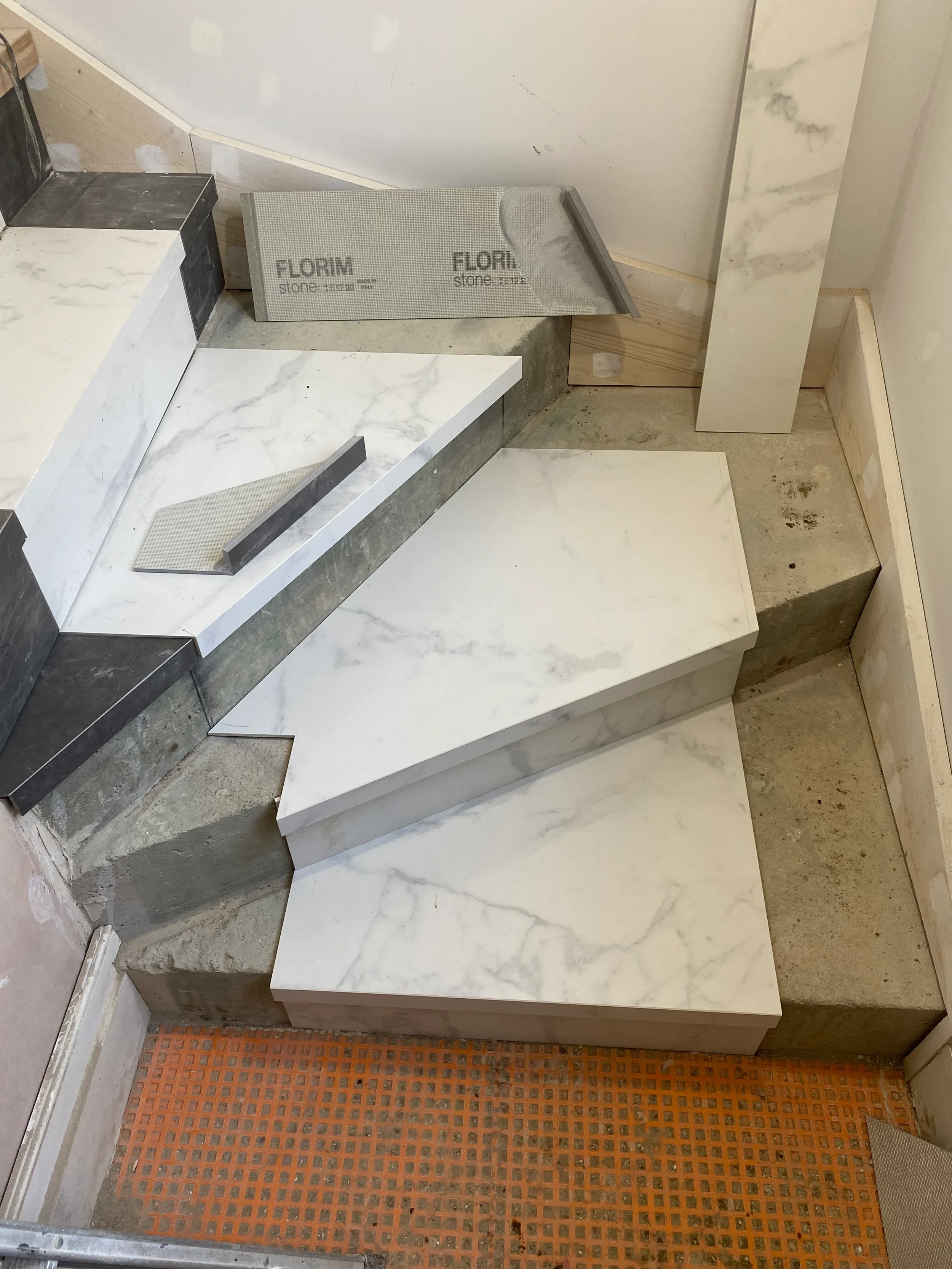 On-site installation of Florim Stone marble-effect porcelain slabs onto a concrete winder staircase.