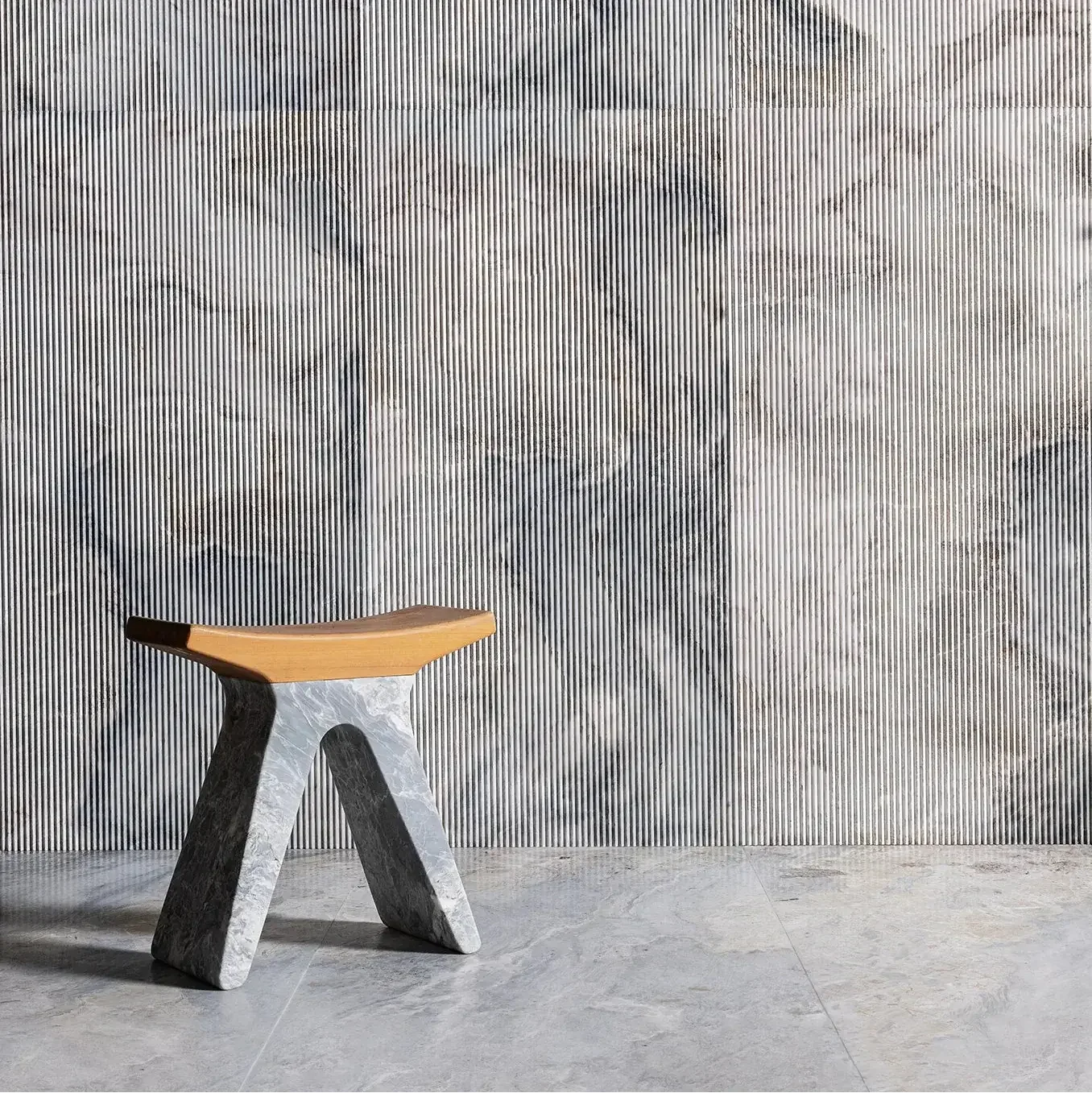The Pigreco stool by the Italian design brand Luce di Carrara, featuring a sculptural base made from reclaimed marble and a smooth, contoured wooden seat, available through PietraCasa