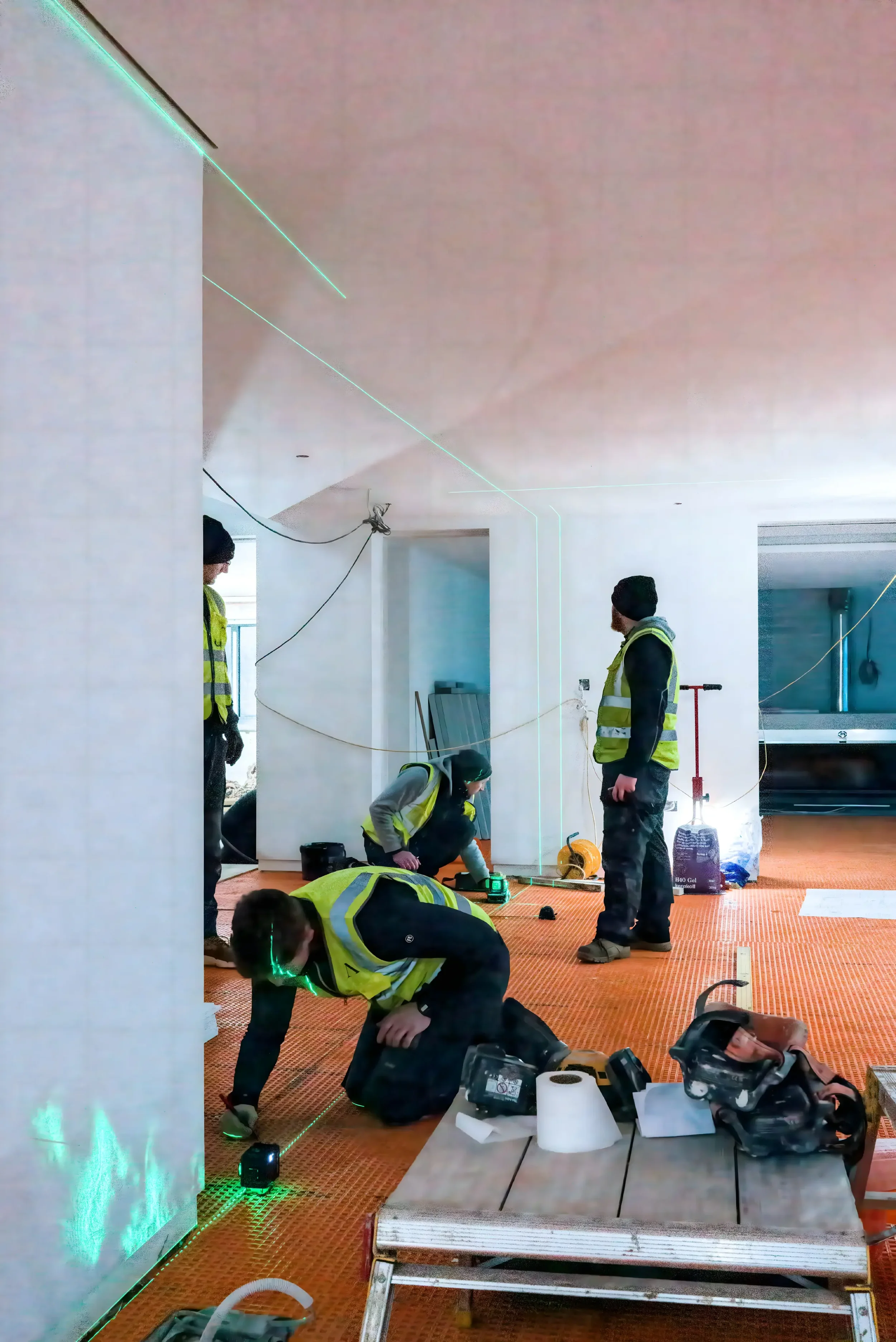Construction professionals using a green laser level to achieve precise alignment during an installation project featuring a Schlüter-DITRA uncoupling membrane, supplied by PietraCasa.