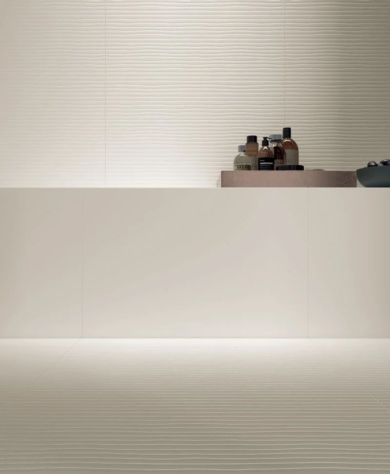 A minimalist bathroom setup featuring the Talco collection by Kronos Ceramiche, showcasing the 'Linea' decor alongside standard 60x120 cm white porcelain stoneware tiles, available through PietraCasa.