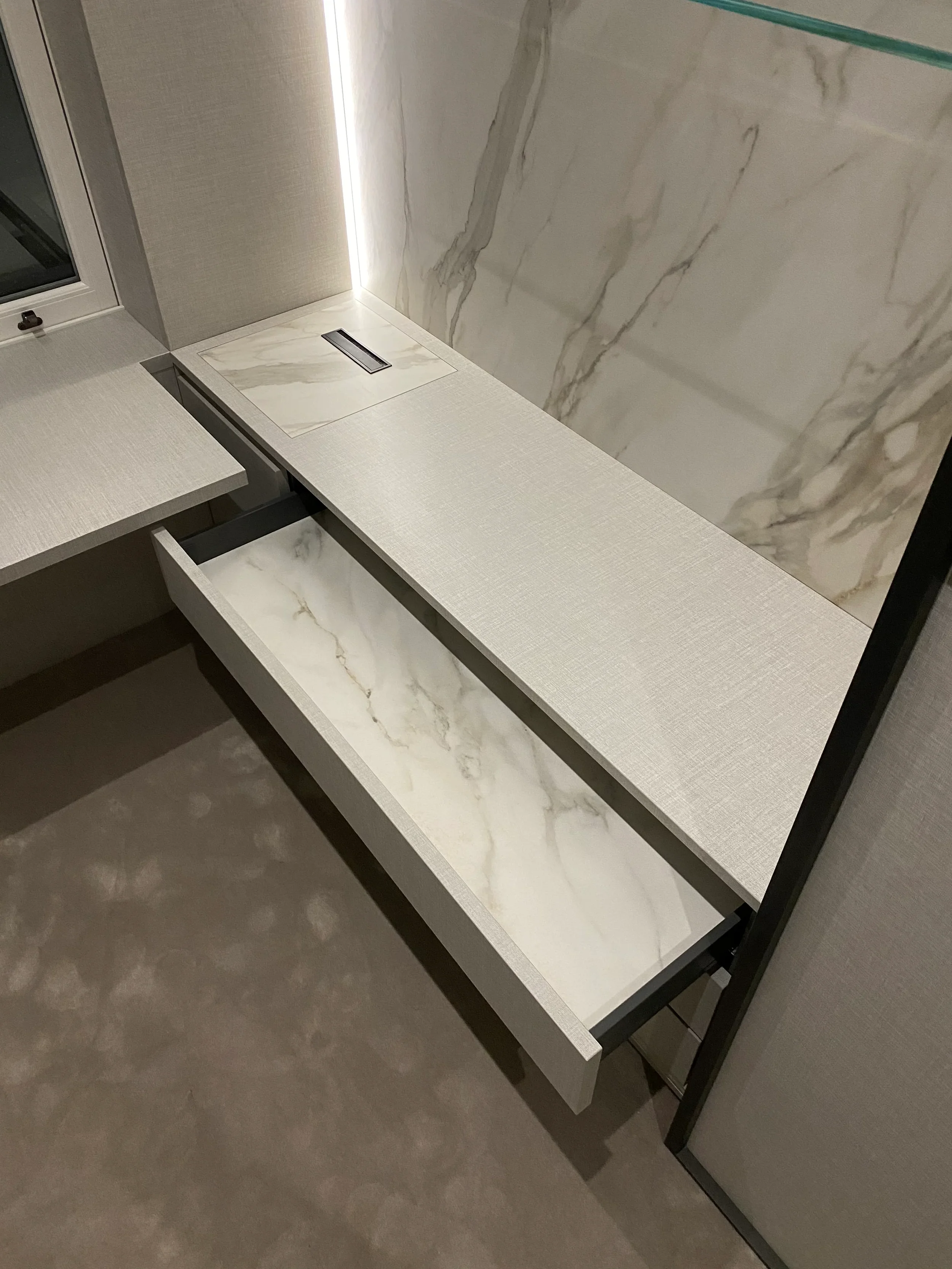 Bespoke vanity dressing table by PietraCasa featuring a textured linen-finish surface, integrated LED strip lighting, and a custom drawer lined with Calacatta marble-effect porcelain.
