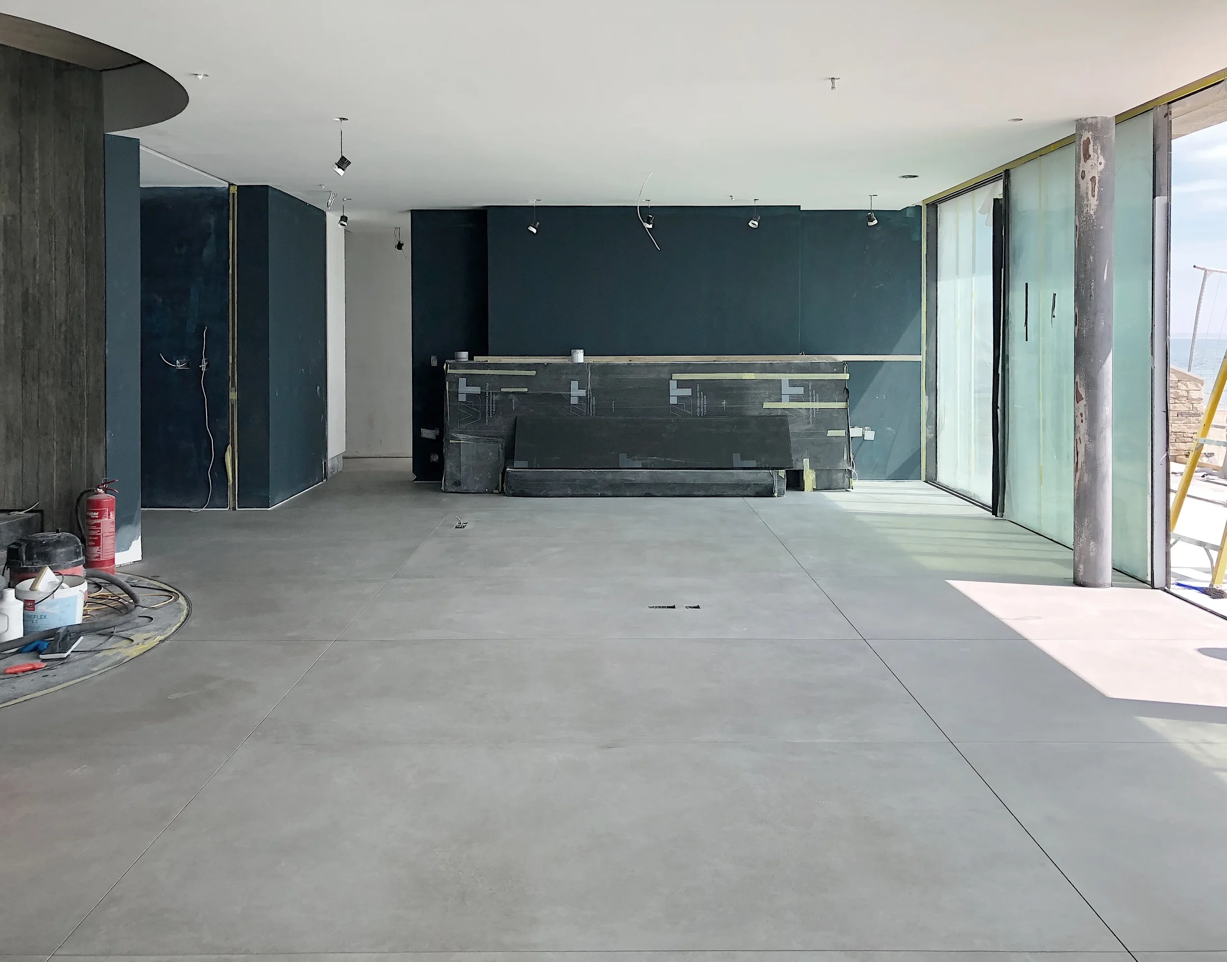 Residential interior under construction featuring premium large-format concrete-effect porcelain floor tiles installed throughout an open-plan living space by PietraCasa.