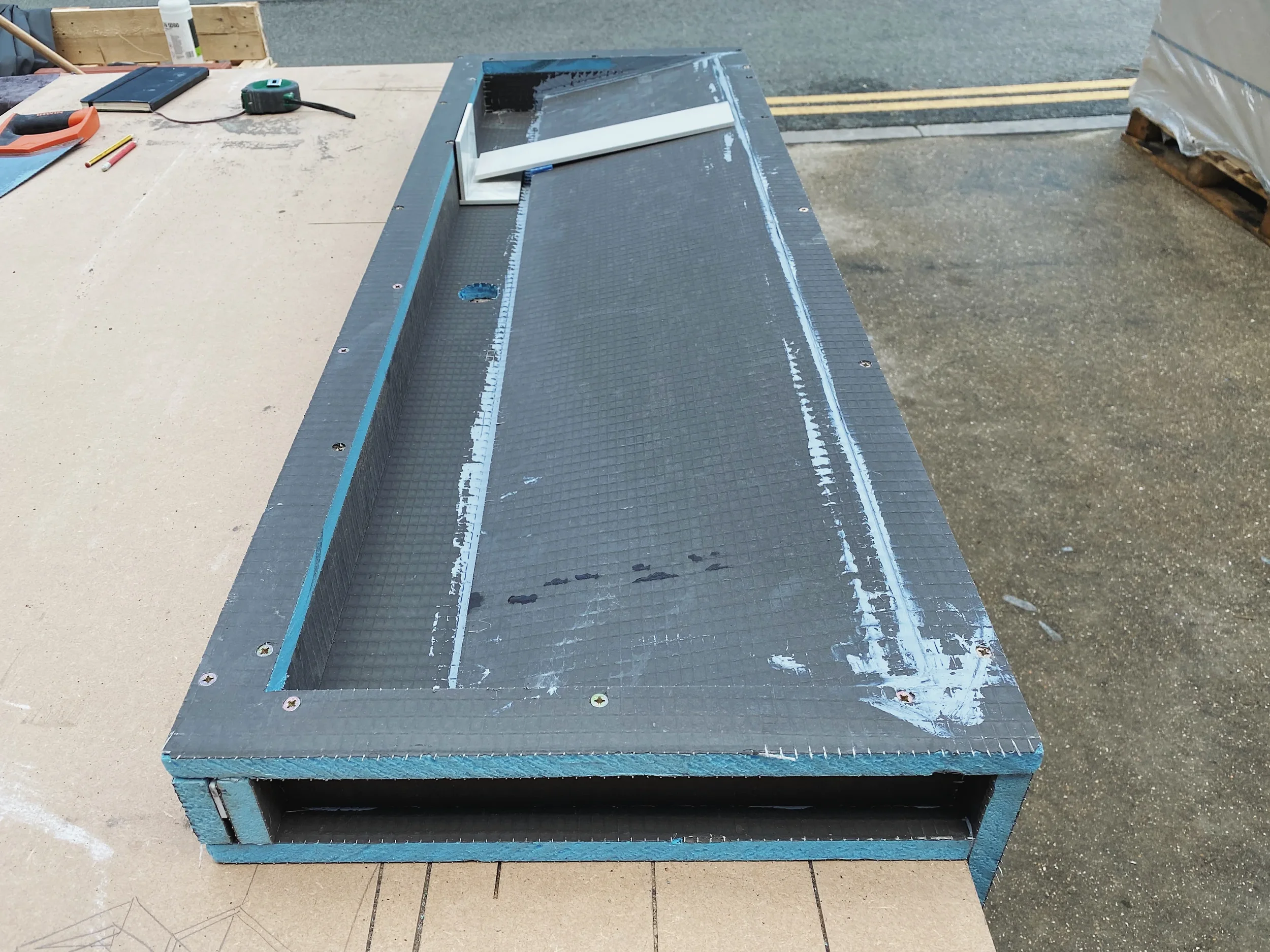 Behind-the-scenes fabrication of a bespoke vanity unit, showing the structural waterproof foam carcass assembly before cladding with large-format porcelain slabs.