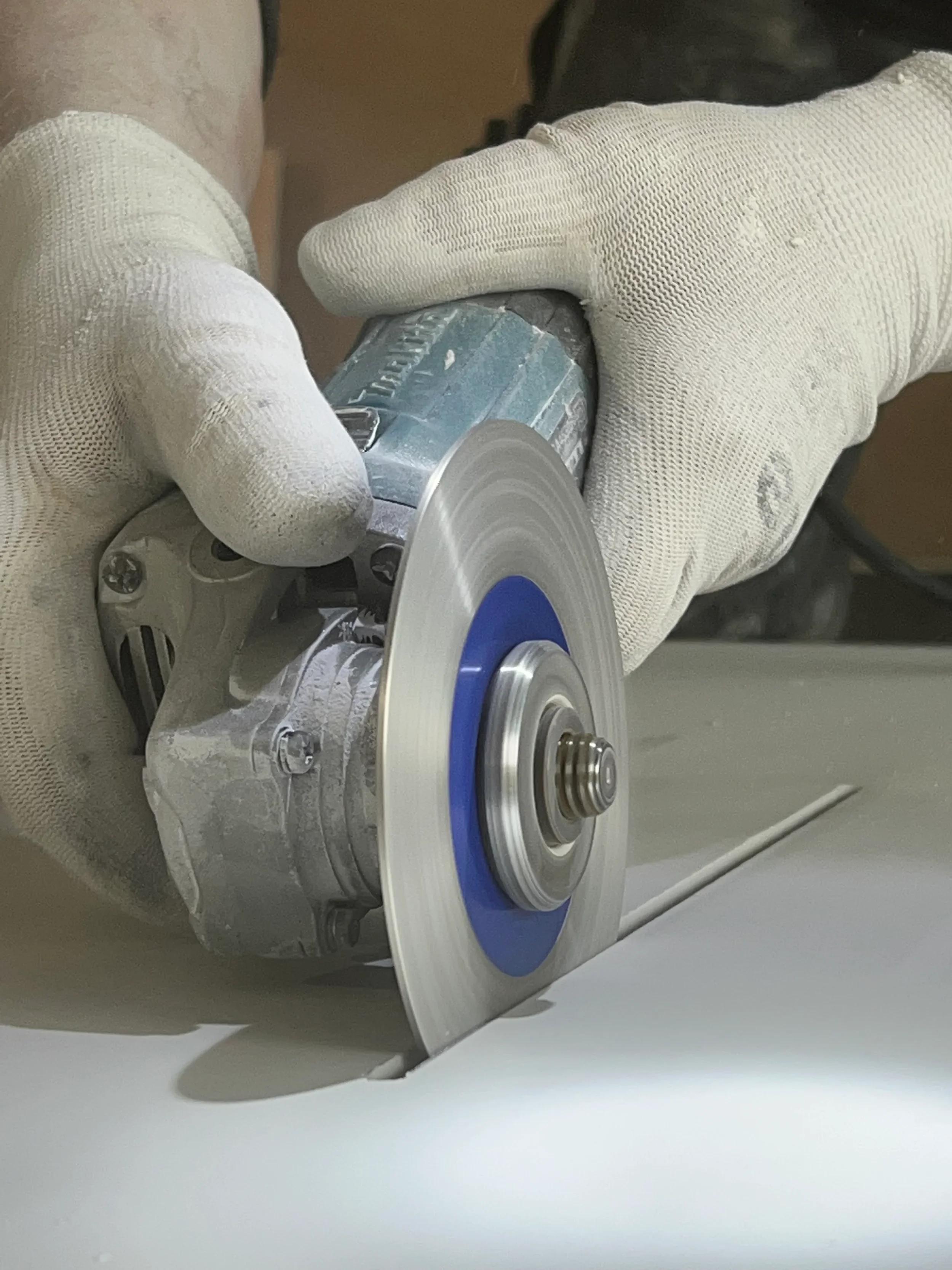 Professional installer using an angle grinder equipped with a Montolit diamond flap disc to precision-finish the edge of a porcelain slab, available through PietraCasa.