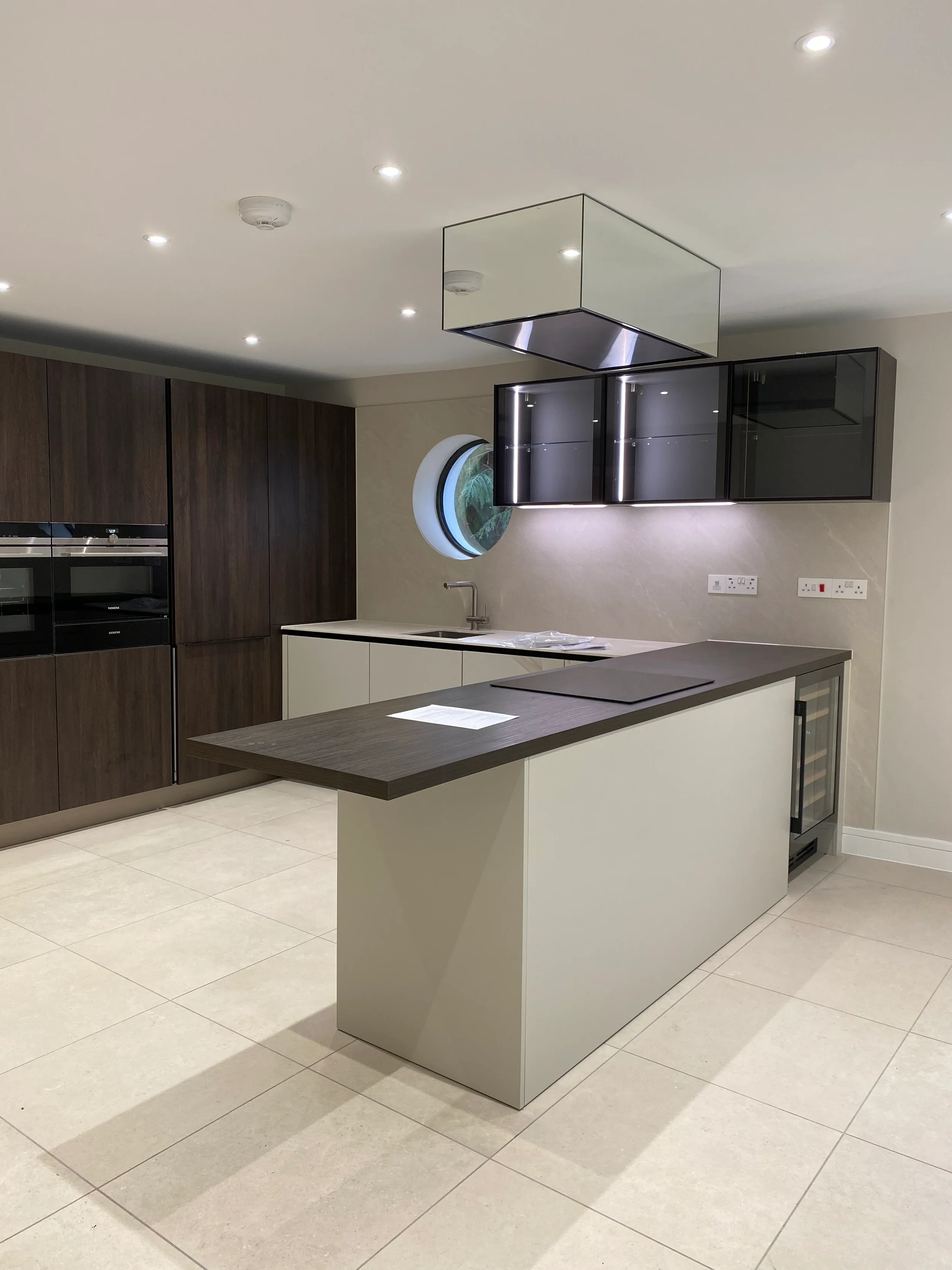 Bespoke rear worktop and splashback panel custom fabricated from light beige porcelain slabs.