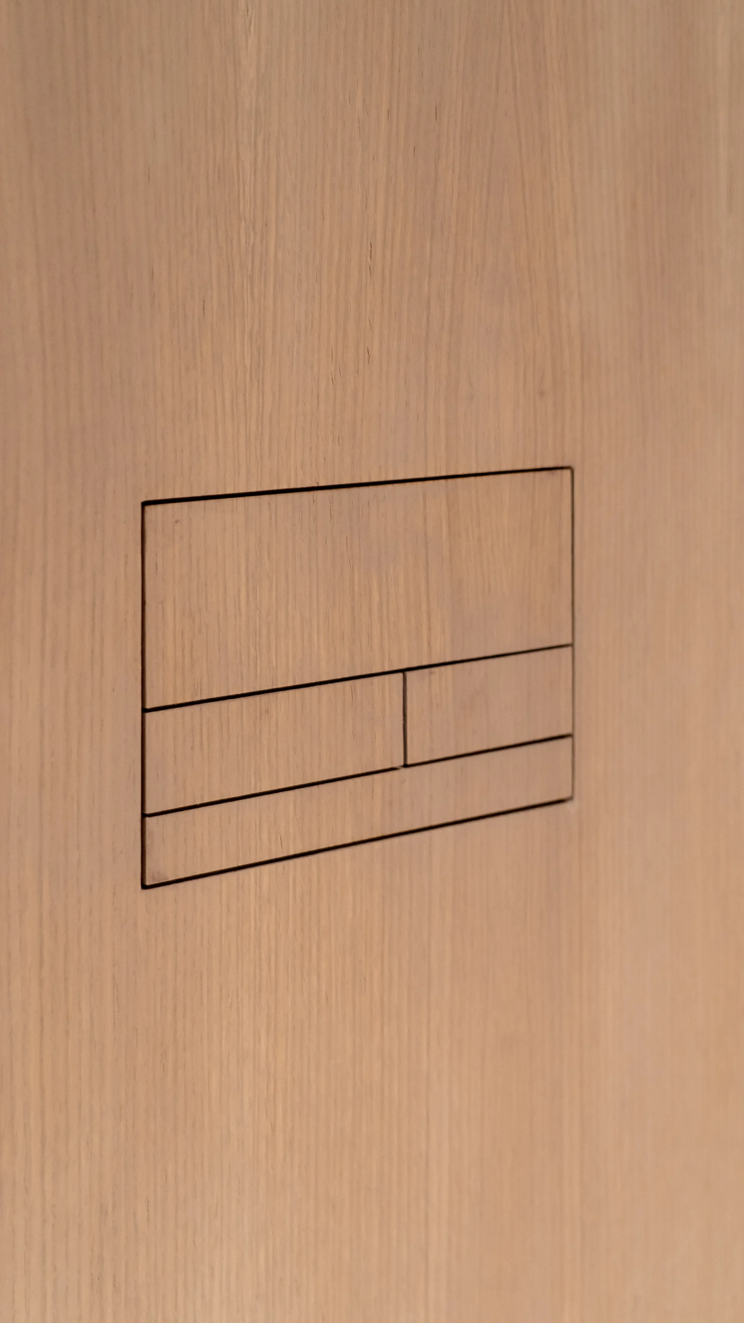 Close-up detail of a seamless Clanea flush plate integrated into a natural wood veneer panel, showcasing PietraCasa's precision installation.