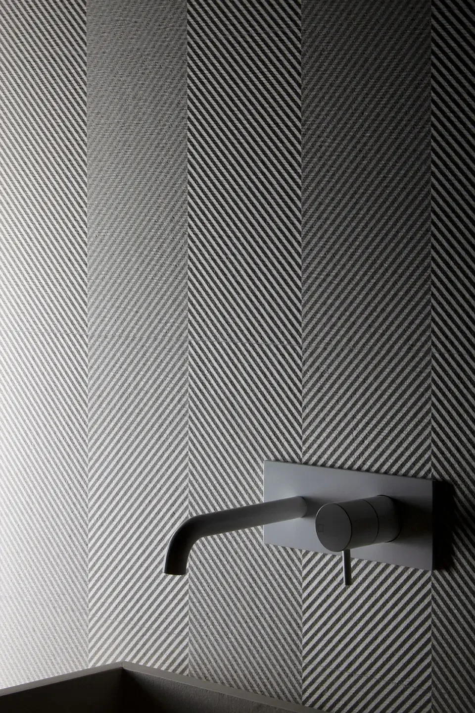 A modern interior design featuring Living Ceramics Ground wall tiles, accented by a sleek, minimalist faucet, available through PietraCasa.