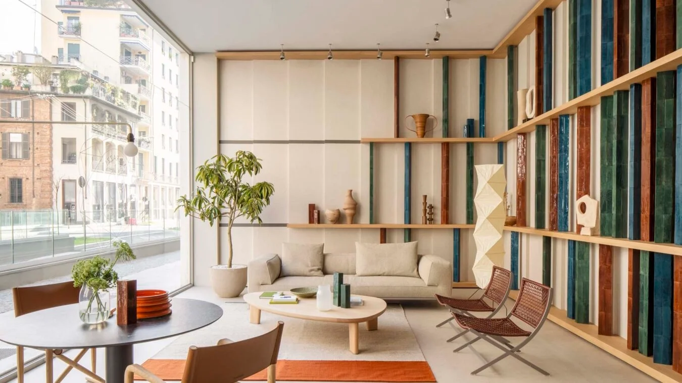 View of the Marazzi showroom in Milan, redesigned by ACPV Architects, featuring contemporary Italian design, large-format wall panels, timber shelving, and vertical ceramic blocks in earthy, blue, and green tones, represented by PietraCasa.