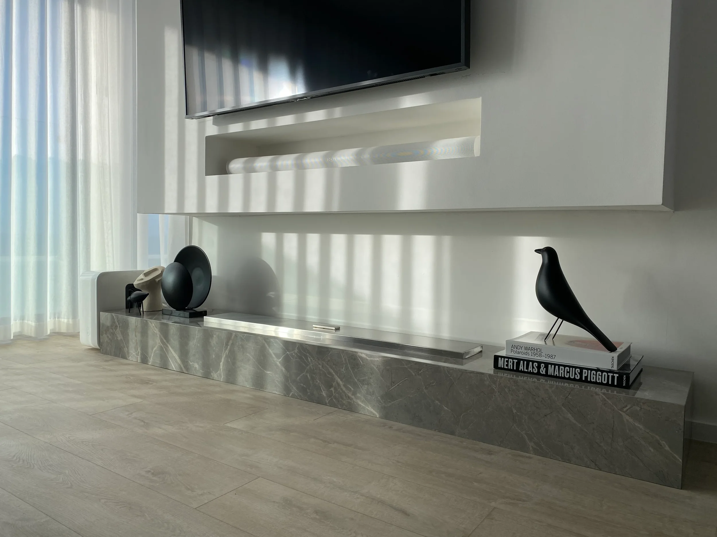 A luxury contemporary media bench custom-fabricated from grey marble-effect porcelain slabs, featuring an integrated flush-mounted linear bioethanol burner and styled with minimalist designer decor.