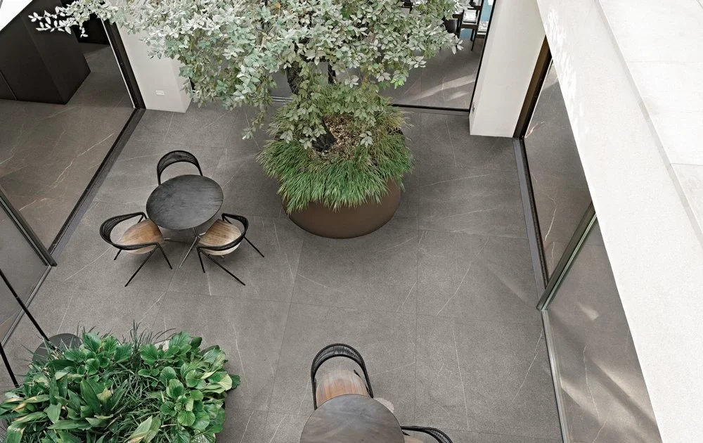 Modern courtyard featuring Florim Coretech porcelain tiles, characterized by refined grey tones, slender white veins, and brownish tinges for a sophisticated stone-look surface, expertly supplied and installed by PietraCasa.