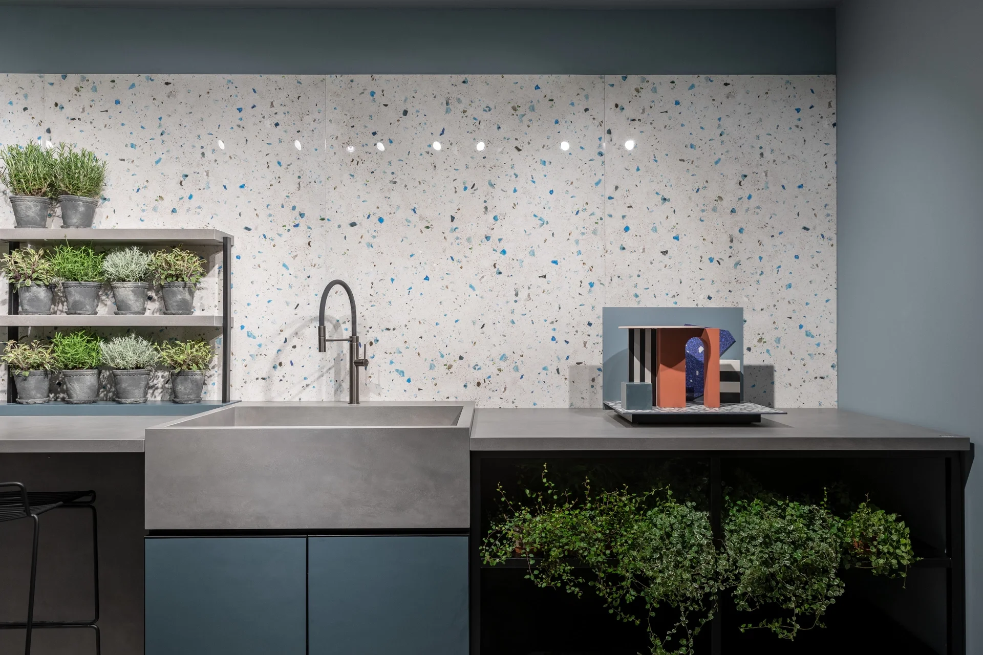 Modern kitchen display featuring Florim stone Collection Cement surfaces, characterized by an eye-catching blue and gray terrazzo-style backsplash, a deep dark gray cement countertop, and integrated sink, expertly supplied and installed by PietraCasa