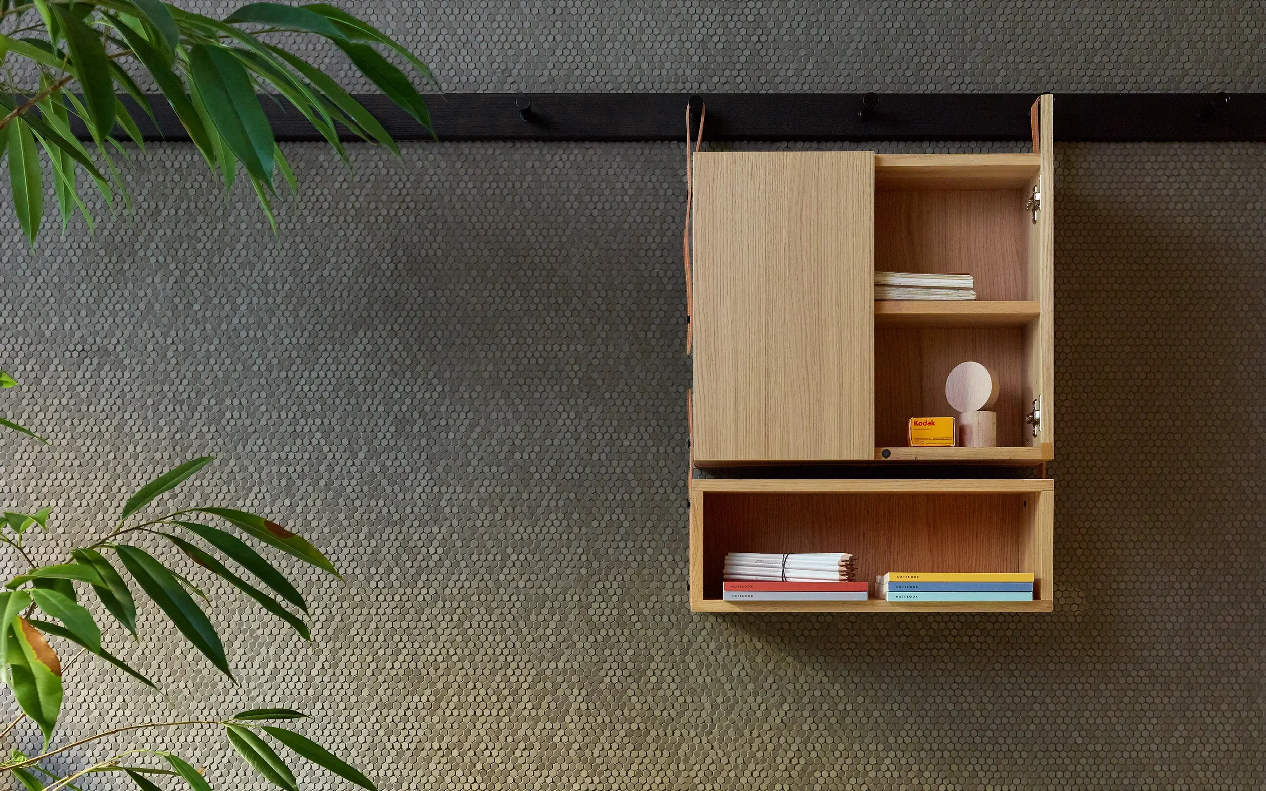 The minimalist Mutina Accents cabinet and shelf system, designed by OEO Studio, mounted against a textured tiled wall, creating a sophisticated display, offered by PietraCasa.