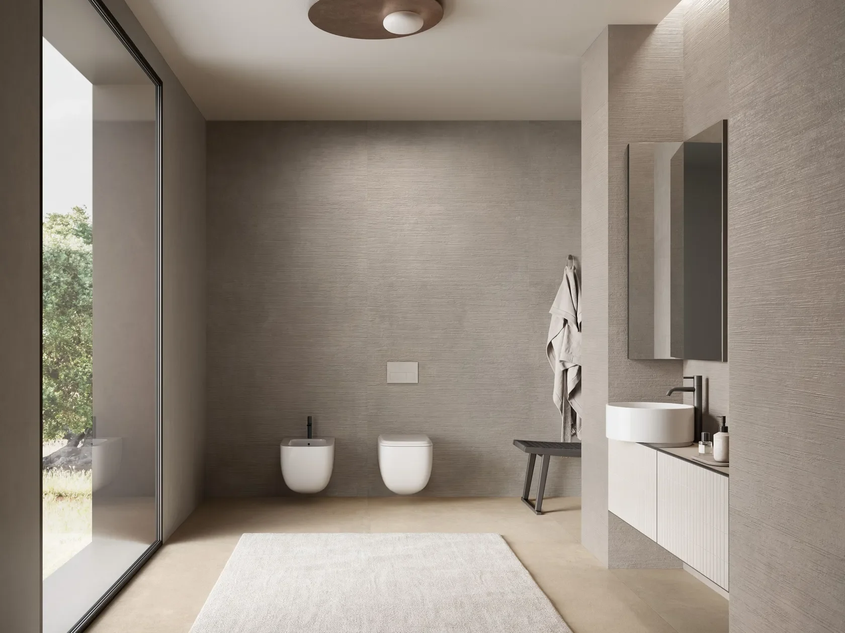 Modern bathroom interior featuring Italgraniti Concrete Impronta porcelain tiles with a textured, neutral-toned finish on walls and floors, complemented by wall-hung sanitaryware and a slimline countertop washbasin, supplied by PietraCasa.
