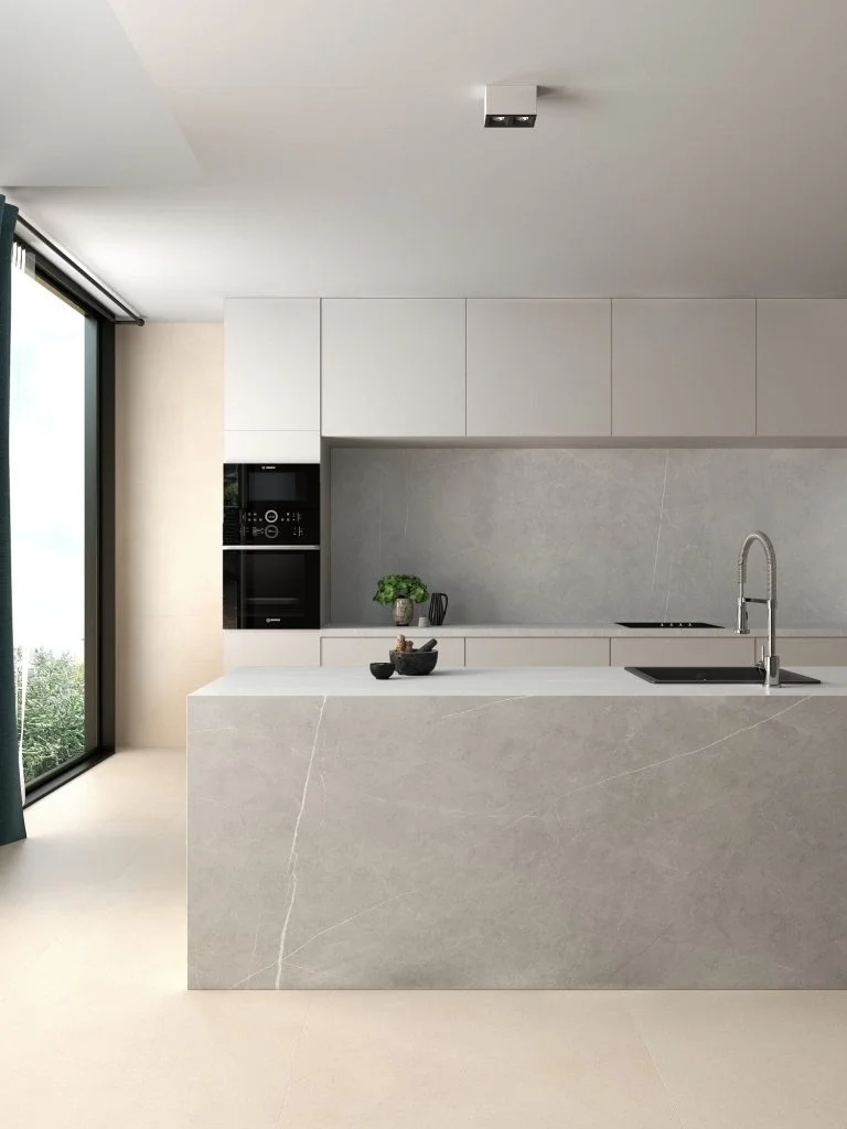 A minimalist, open-concept kitchen featuring Living Ceramics Allure Light Grey porcelain tiles, known for their elegant marble-like veining, available through PietraCasa.